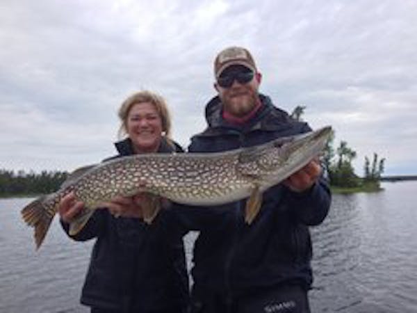 Nancy Weidenfeller of Minnetonka, left, needed a little unidentified assistance to display this 39-inch northern she caught on Lake Saint Joe in Ontar