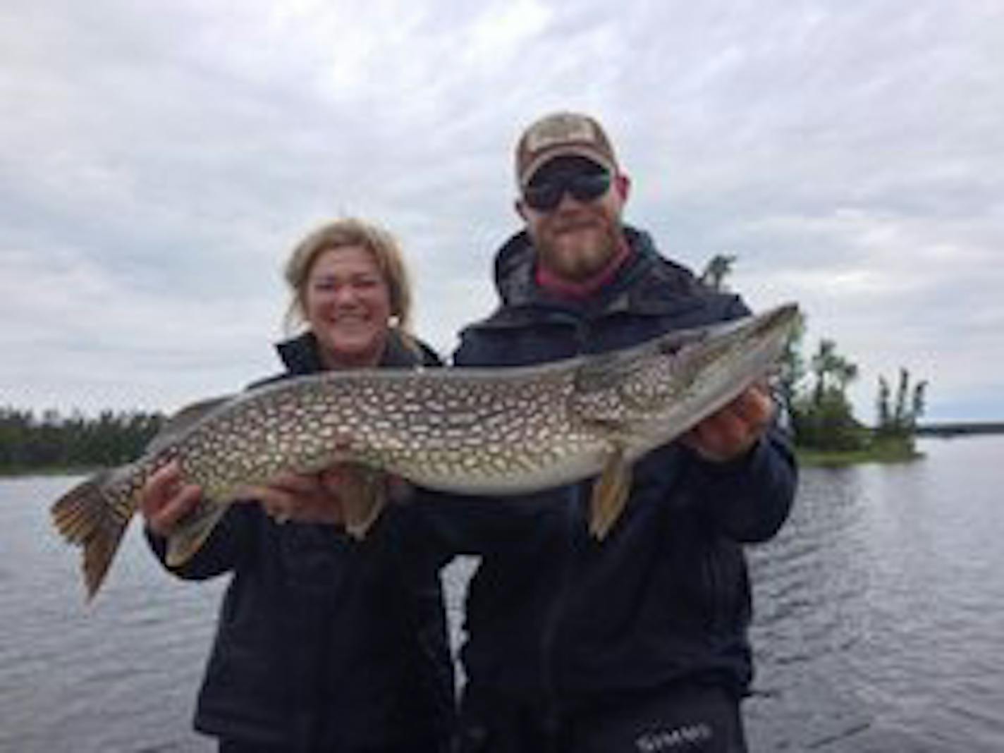 Nancy Weidenfeller of Minnetonka, left, needed a little unidentified assistance to display this 39-inch northern she caught on Lake Saint Joe in Ontario.