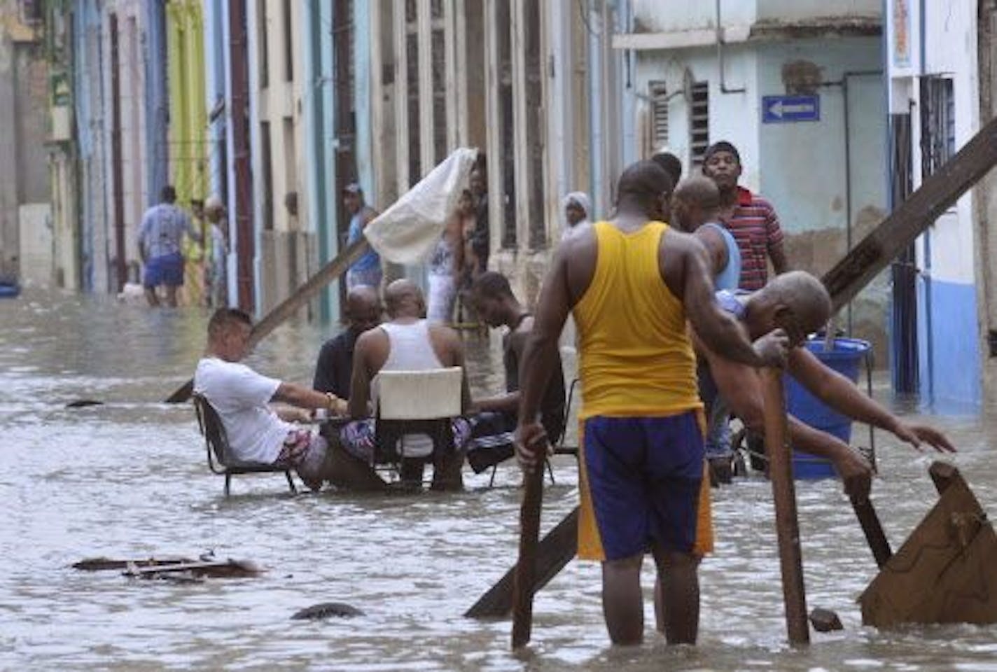 In this Sunday, Sept. 10, 2017 photo released by Granma, men play dominoes in the middle of a flooded street as others pull broken furniture from calf-high water in the aftermath Hurricane Irma, in Havana, Cuba. Eddy Dennis, a grey-haired 51-year-old parking attendant pulling furniture, said the scene was one of neighborly cooperation and mutual effort in the face of the city�s worst flooding in years, if not decades. �It was something communal that all the neighbors were doing in the spirit of