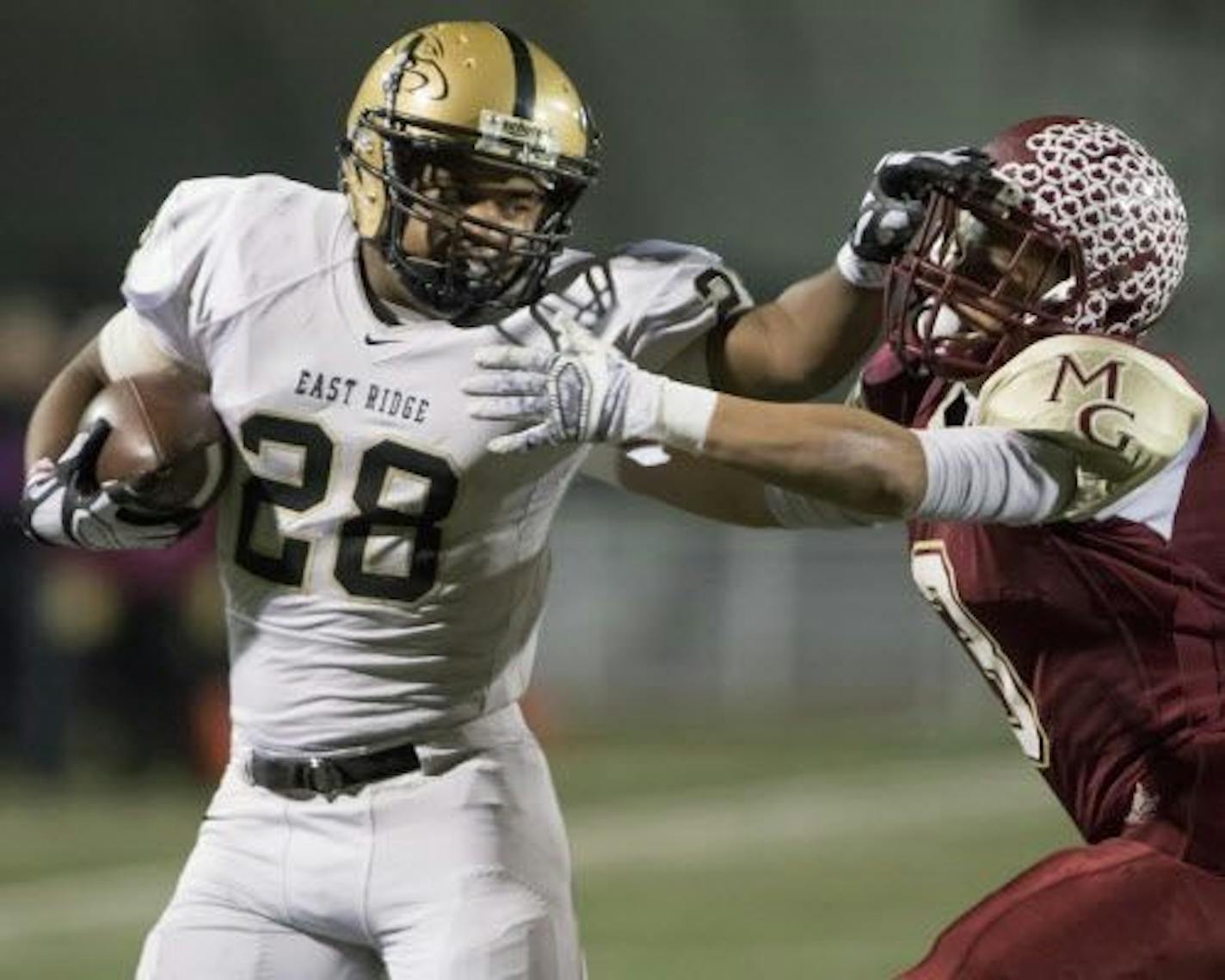 East Ridge running back Dominik London (28) stiff arms Maple Grove running back Isaac Collins (3) after a big gain as the Maple Grove Crimson faced the East Ridge Raptors Class the Class 6A MSHSL Football semifinals.