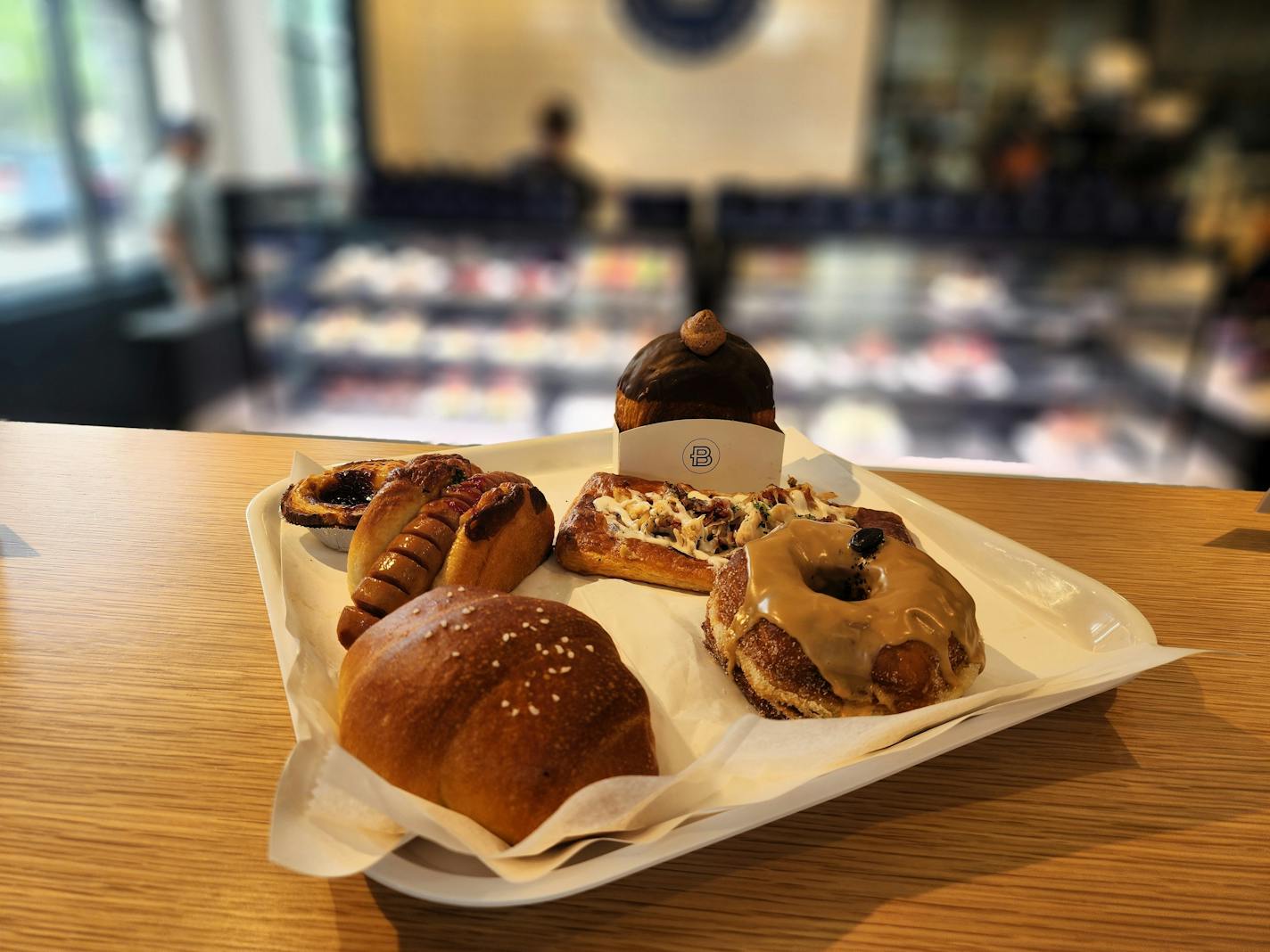 A tray with several pastries including a roll, a circular croissant, a doughnut and a hot dog in a pastry bun