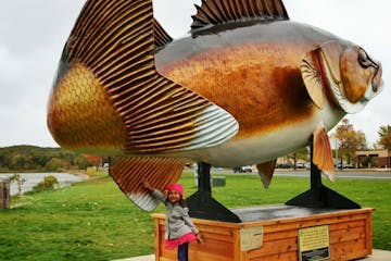 Mila, one of the kids from the Mali Mish family, at the walleye statue in Garrison. The family, which travels the country in an Airstream trailer, has