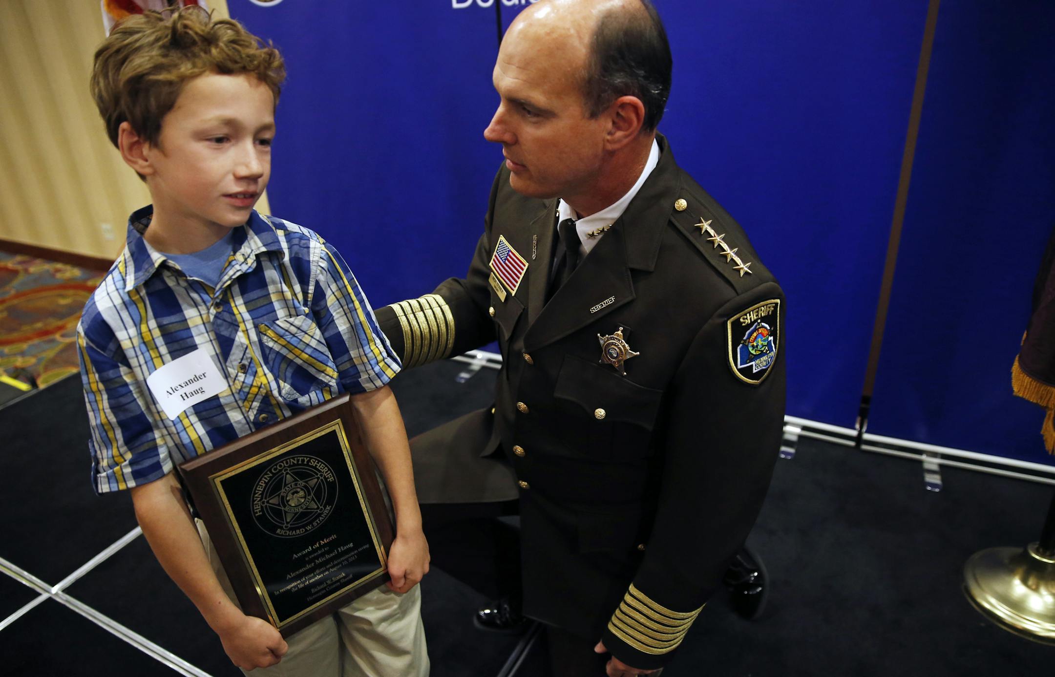 At the Tribute to Extraordinary Citizens on Thursday night in Brooklyn Park, Hennepin County Sheriff Rich Stanek knelt down to congratulate pint-size hero Alexander Haug, 9, who helped save his brother Nathan, 6, from drowning in their uncle’s swimming pool. Alexander was one of 27 citizens honored with awards.