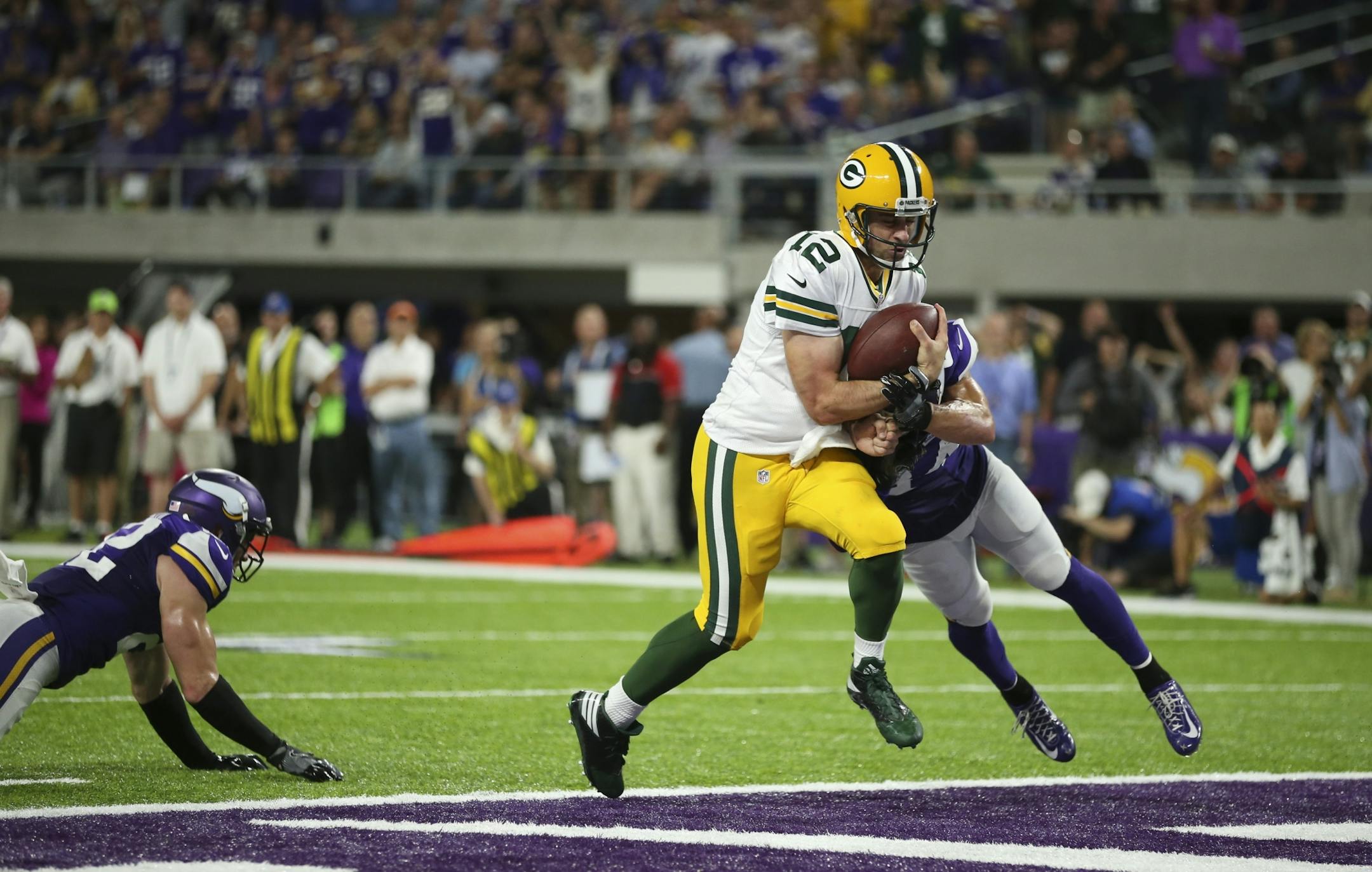 Vikings strong safety Andrew Sendejo (34) hit Green Bay Packers quarterback Aaron Rodgers (12) hard in the end zone after his fourth quarter touchdown brought the Packers to within three points of the Vikings.