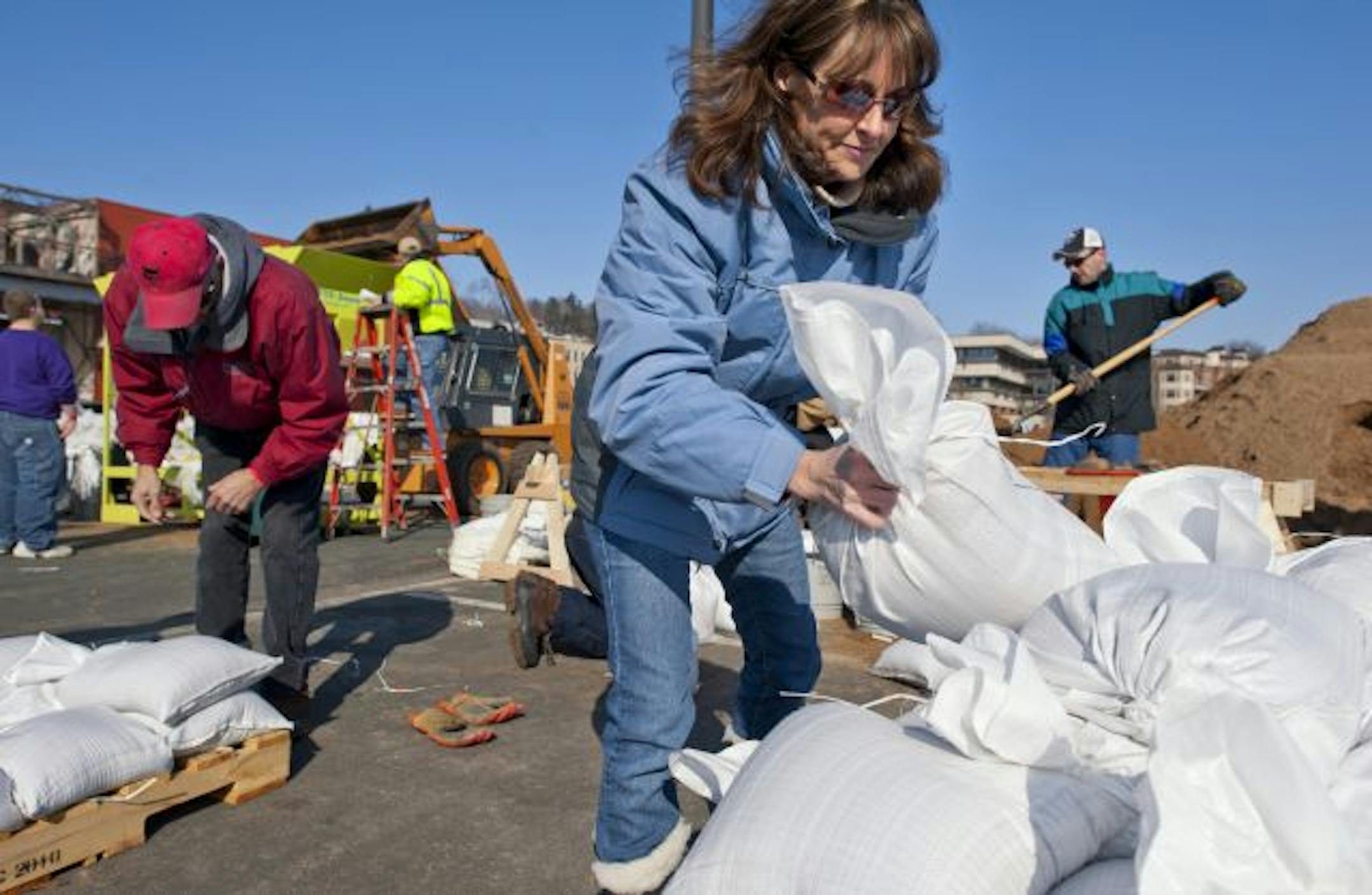 In Stillwater on Monday, Carole Krogh stacked sandbags near the St. Croix River. Stillwater is expecting record flooding and officials there are looking to fill 100,000 sandbags over the next three weeks to be used to keep floodwaters at bay.