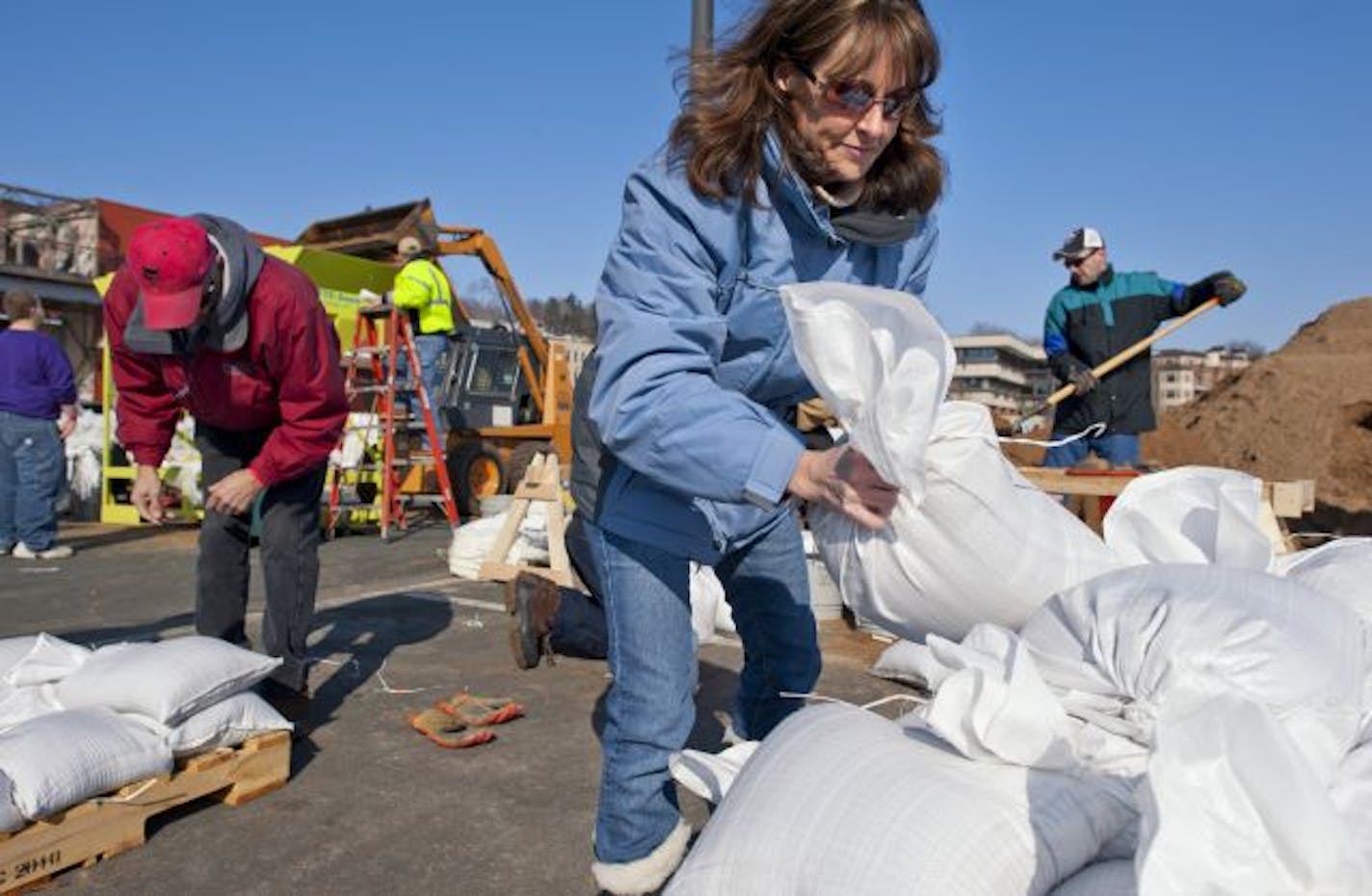 In Stillwater on Monday, Carole Krogh stacked sandbags near the St. Croix River. Stillwater is expecting record flooding and officials there are looking to fill 100,000 sandbags over the next three weeks to be used to keep floodwaters at bay.