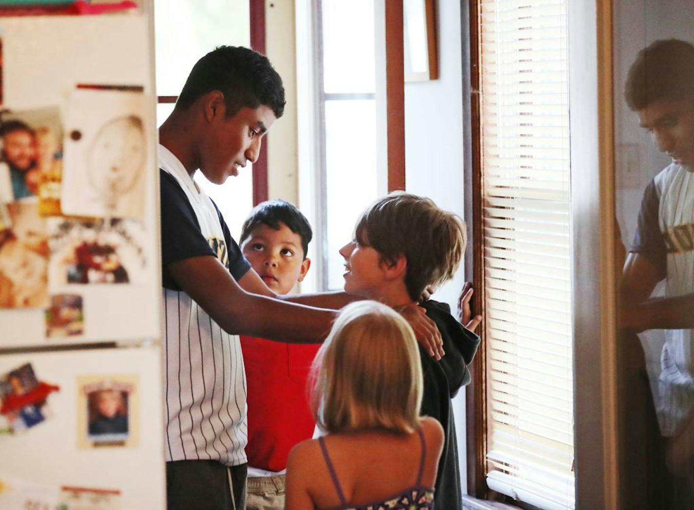 Daniel Arias, 15, the son of Honduran refugee Nuria Arias, places his hands on the shoulders of Owen Sigelkow, 11, the son of Ry Sigelkow, a Mennonite pastor, who is hosting the Arias family, as the boys talked following dinner at the Sigelkow home Saturday, Aug. 4, 2018, in Minneapolis, MN. Looking on is Brian Arias, 5.