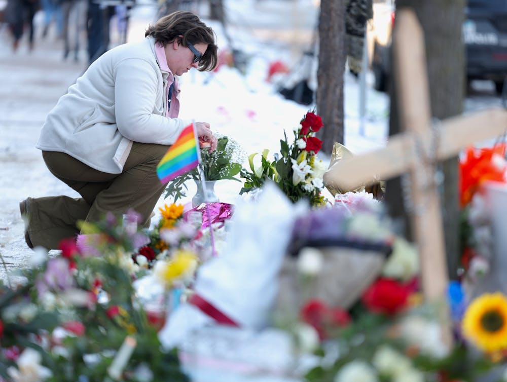 Breeana Gerber kneels at a growing memorial for Renee Nicole Good on Jan. 9 in Minneapolis, near where she was fatally shot by an ICE agent on Jan. 7. “I woke up this morning feeling emotional about this and seeing history repeat itself again,” Gerber said.