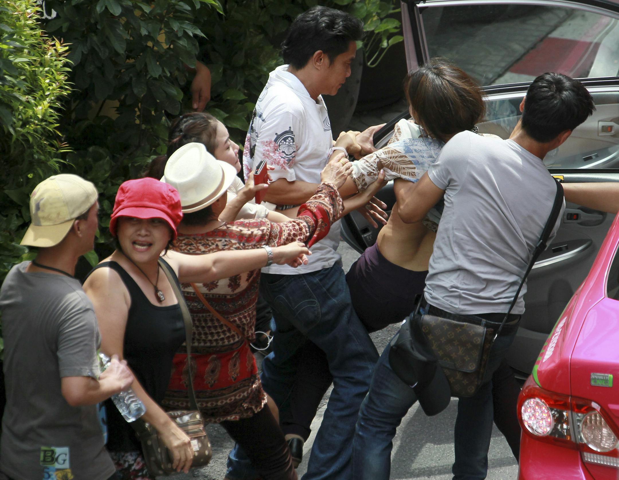 Thai plain cloth police officers, right, and 3rd right, force a protester on to a taxi during an anti-coup demonstration in Bangkok, Thailand Sunday, June 1, 2014. Hundreds of demonstrators shouting "Freedom!" and "Democracy!" gathered Sunday near a major shopping mall in downtown Bangkok to denounce the country's May 22 coup despite a lockdown by soldiers of some of the city's major intersections. (AP Photo/Wason Wanichakorn)