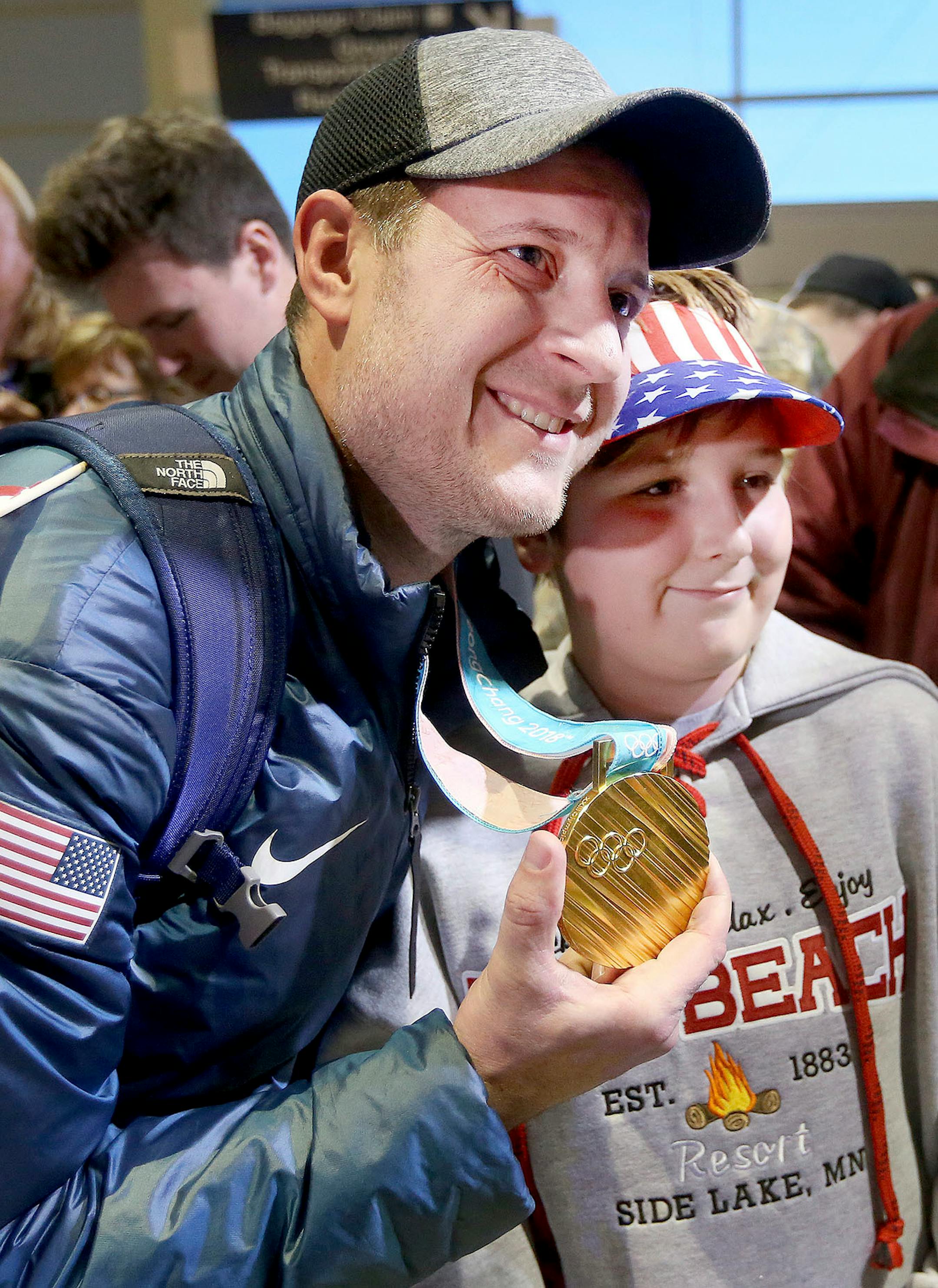 Aaron Rols of Hibbing poses with John Shuster who holds his Olympic gold medal. Bob King / rking@duluthnews.com