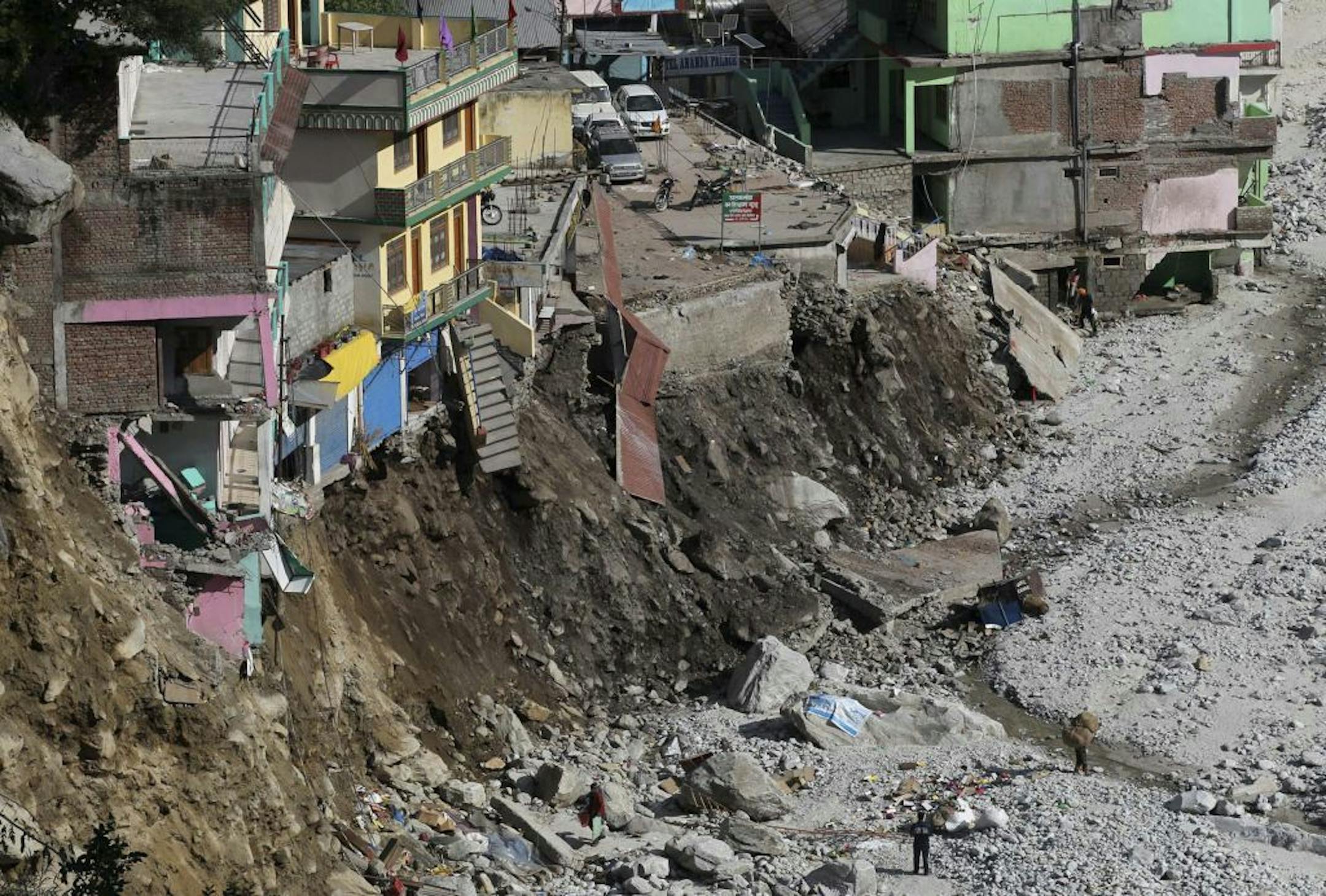 FILE -In this June 22, 2013 file photo, vehicles are parked near the buildings damaged by floods and landslides in Govindghat in the northern India state of Uttarakhand, India. A top Indian official said more than 5,700 people were missing since last month's devastating floods that ravaged northern India are now presumed dead.