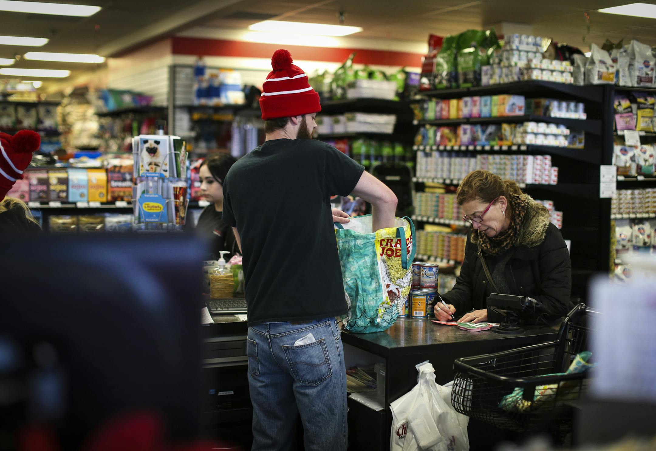 Evan Carlson bagged Jodi Davis' cat food as she filled out a Paw Print Fundraiser card at Chuck and Don's Pet Food and Supplies in Minneapolis, Minn. on Friday, December 19, 2014. ] REN&#xc9;E JONES SCHNEIDER reneejones@startribune.com