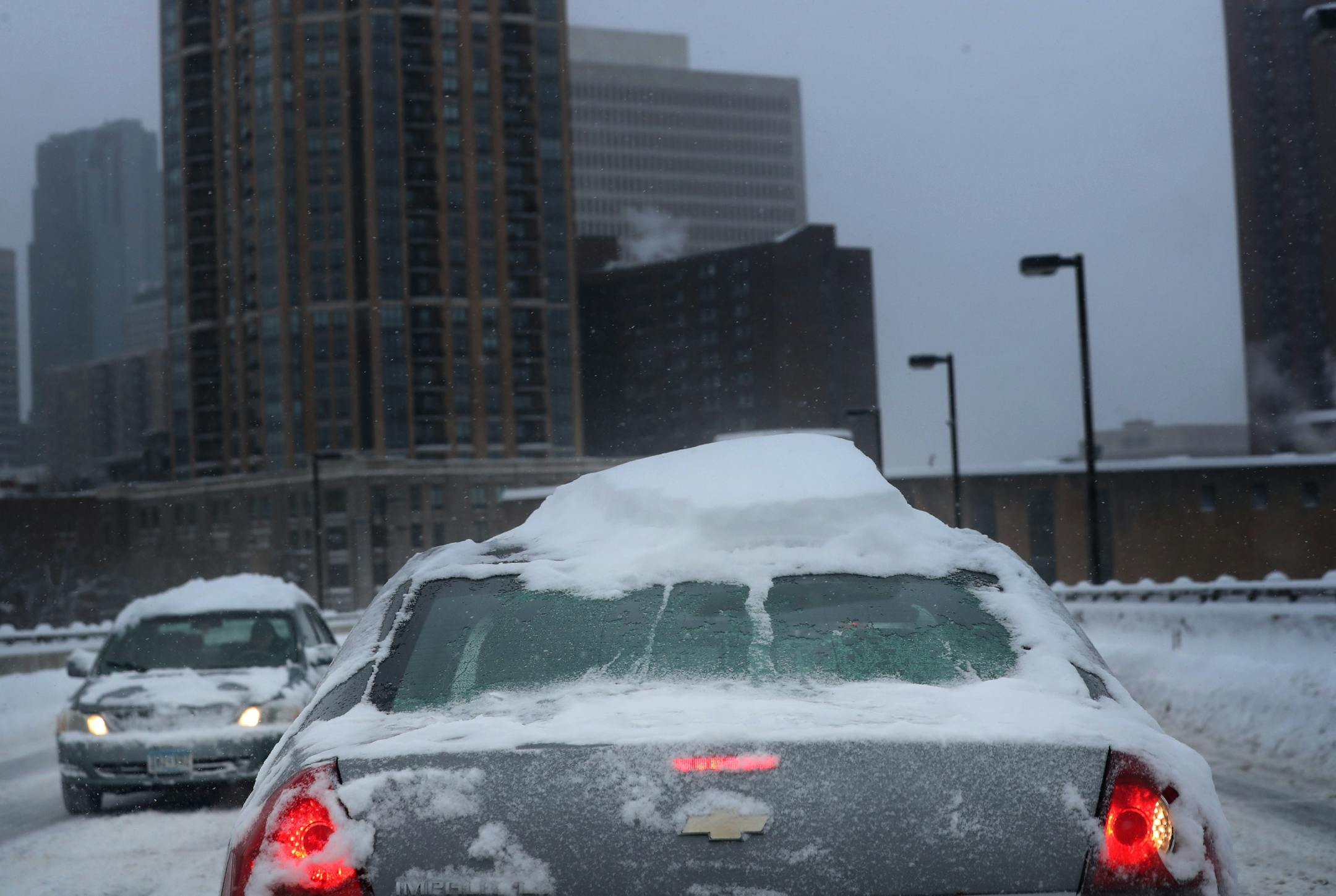The latest round of winter clings to the top of a car traveling along Third Ave. S. in Minneapolis.