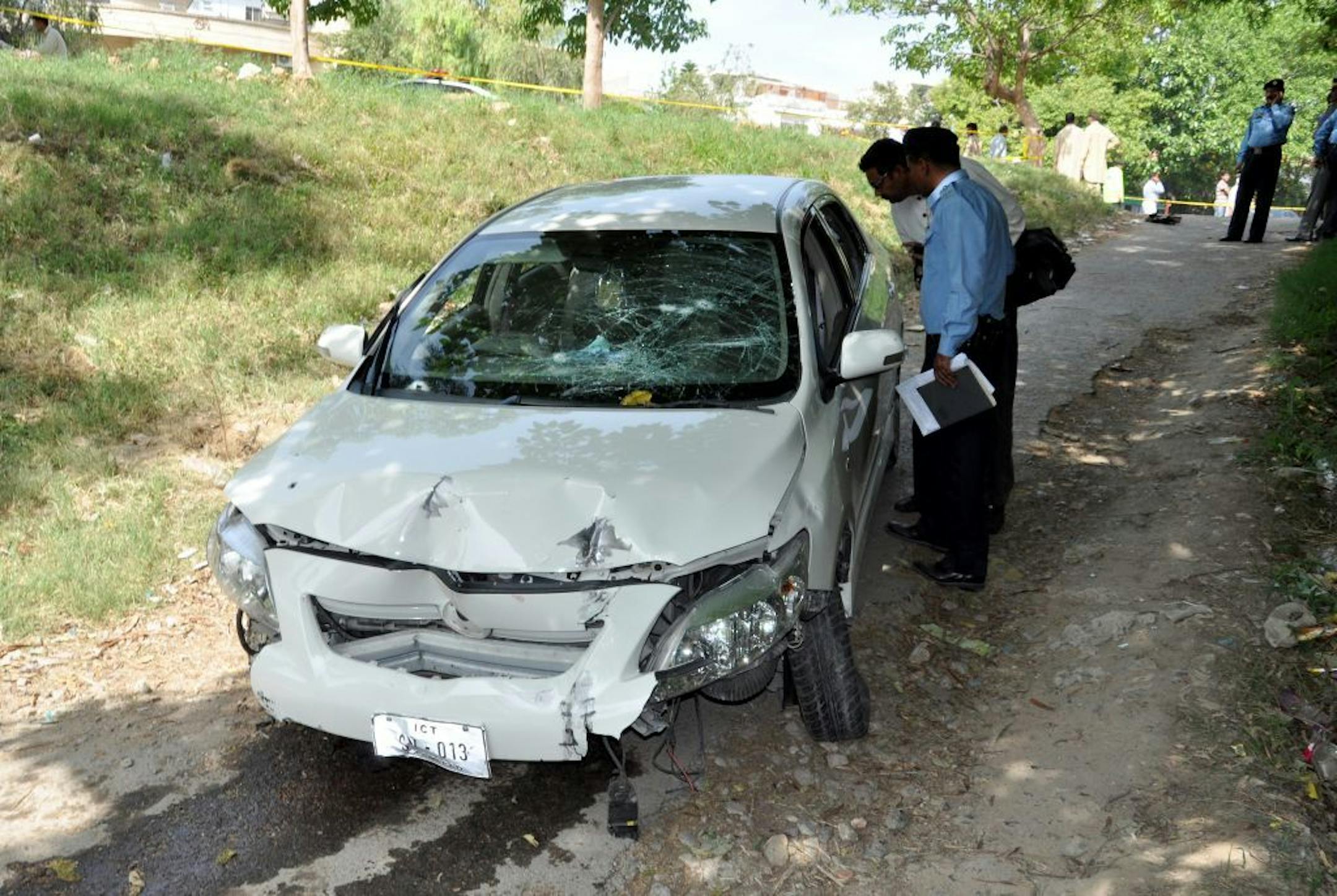 Pakistani police officers examine the car of prosecutor Chaudhry Zulfikar who was targeted by gunmen in Islamabad, Pakistan on Friday, May 3, 2013. Gunmen killed Pakistan's lead prosecutor investigating the assassination of former prime minister Benazir Bhutto as he drove to court in the capital on Friday, throwing the case that also involves former ruler Pervez Musharraf into disarray.