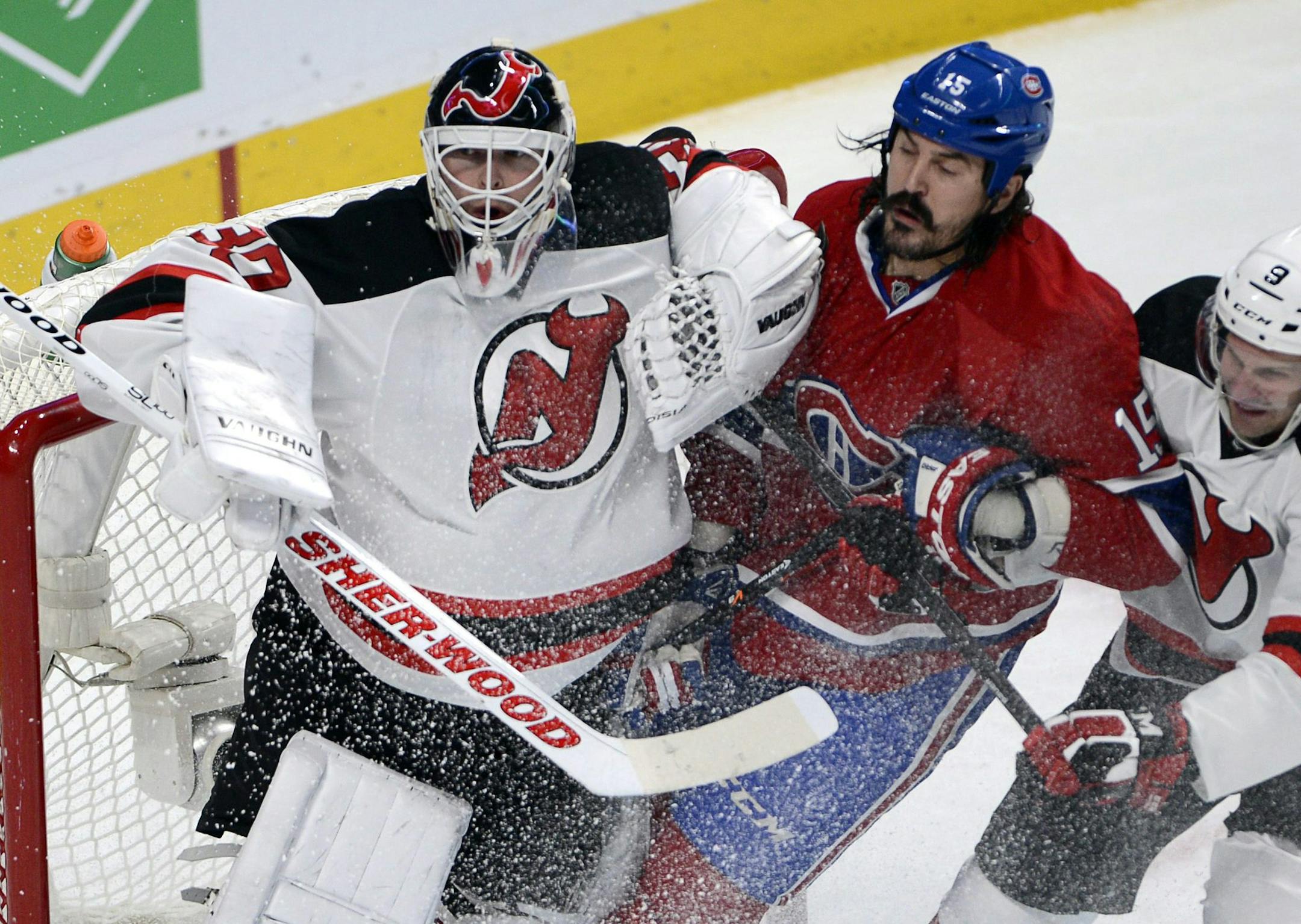 Montreal Canadiens right wing George Parros (15) is sandwiched between New Jersey Devils goalie Martin Brodeur (30) and Devils right wing Mike Sislo (9) during first period National Hockey League action, Tuesday, Jan. 14, 2014, in Montreal. (AP Photo/The Canadian Press, Ryan Remiorz)