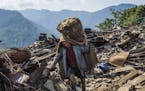 Santa man Ghale, 60, sorts through rubble in search of belongings in Barpak, Nepal, May 6, 2015. The village, high above a picturesque valley, lies at