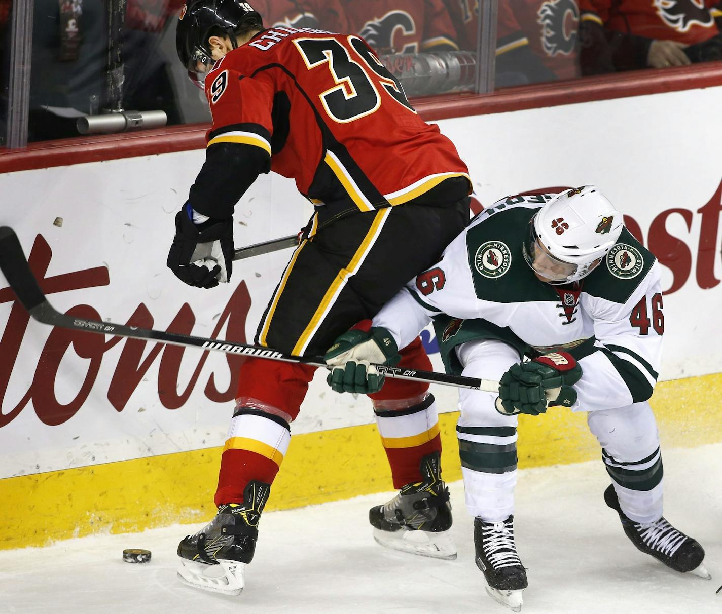 Minnesota Wild's Jared Spurgeon, right, reaches for the puck past Calgary Flames' Alex Chiasson during first-period NHL hockey game action in Calgary, Alberta, Friday, Dec. 2, 2016. (Larry MacDougal/The Canadian Press via AP)