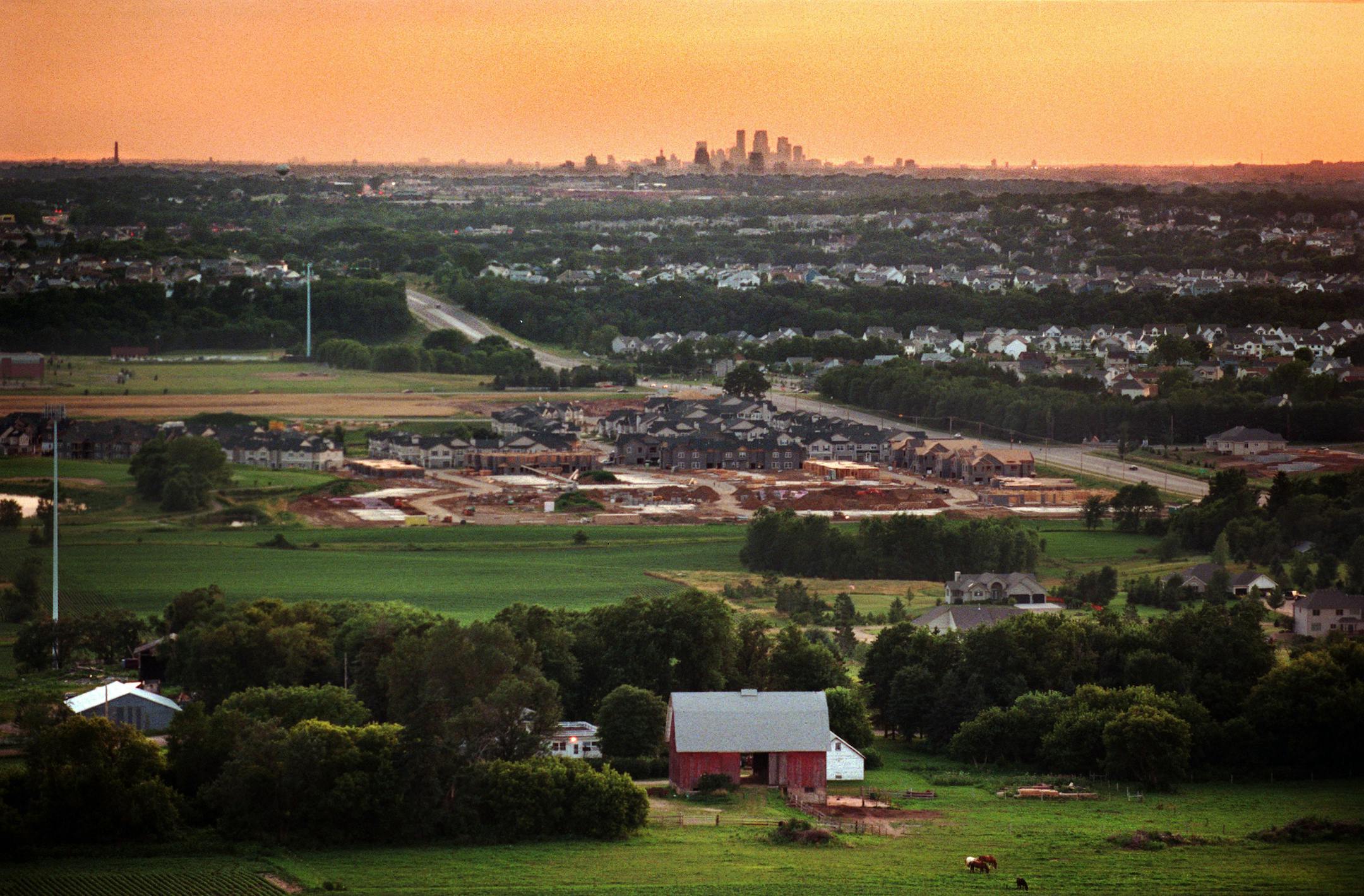 For our next story in a series on sprawl, we want to show sprawl in its various forms --. -- (THIS PHOTO_7/12/99_Woodbury) - Looking west toward the core cities of Minneapolis and St.Paul from the edge of the developing metro area. In the foreground is the Jim Currell farm. His father, John, bought 225 acres of land in 1950. He came here from Iowa to study agriculture, and then bought the farm. He later bought the farm across the road. At the time the farm had it all, dairy, beef, sheep and hogs