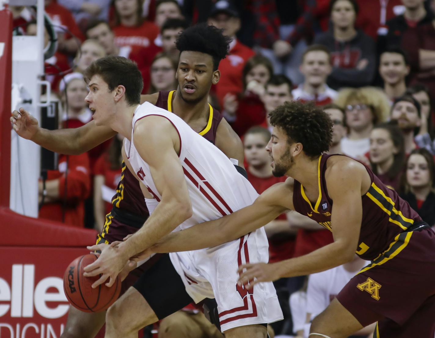 Wisconsin's Ethan Happ (22) drives against Minnesota's Eric Curry, behind, and Gabe Kalscheur, right, during the first half of an NCAA college basketball game Thursday, Jan. 3, 2019, in Madison, Wis. (AP Photo/Andy Manis)