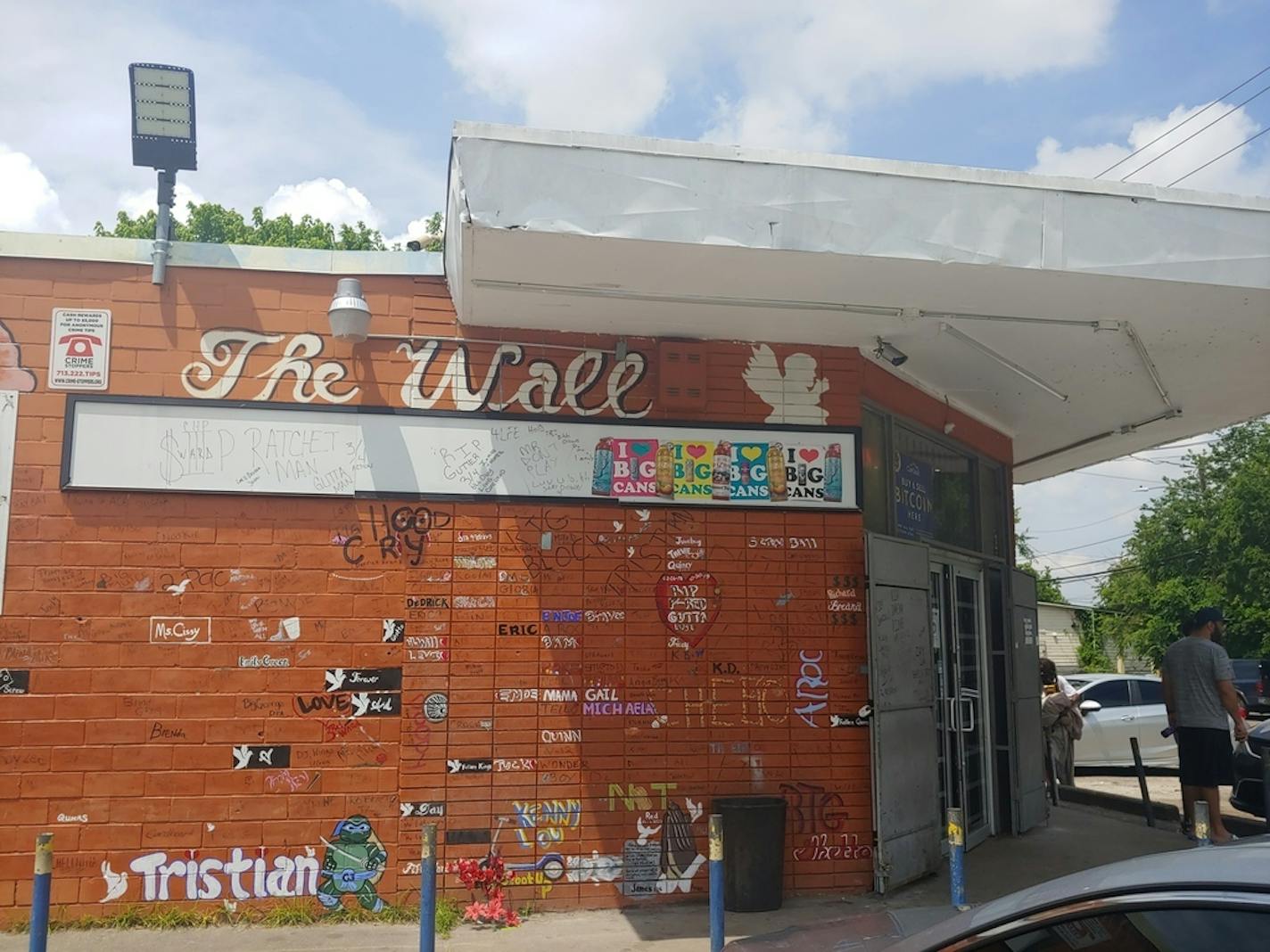 The corner store across from Cuney Homes in George Floyd's old neighborhood features a wall where people record the names of locals who die. A mural of Floyd is on an adjoining wall. (Maya Rao/Star Tribune)