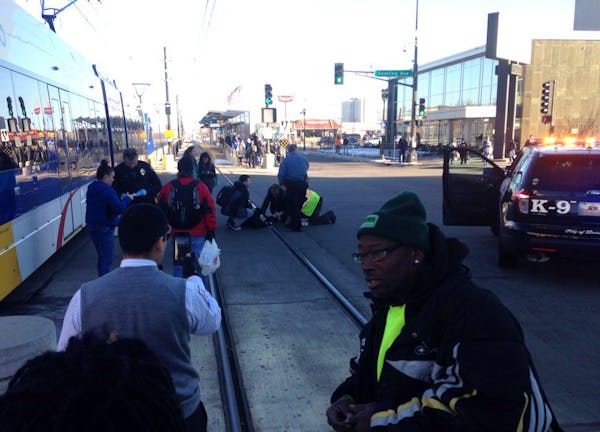 A pedestrian is given aid after being hit by a Green Line train in St. Paul on Friday afternoon.