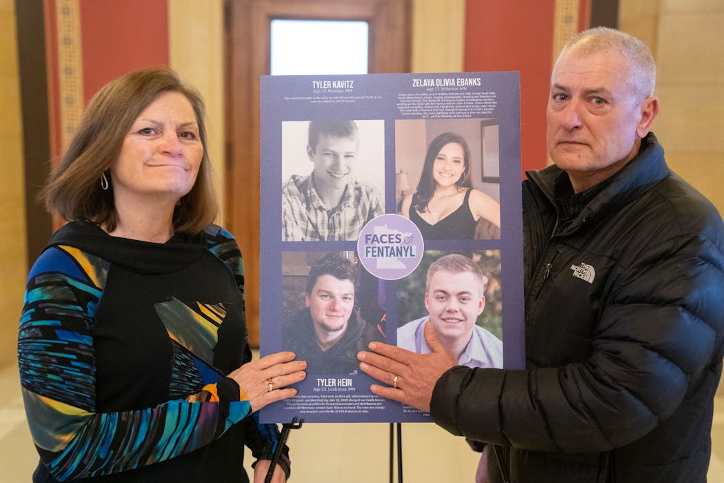 Michele and Jerry Hein pose for a portrait next to a photo of their son, Tyler, who died from a fentanyl overdose, as part of a display the Heins organized at the Minnesota State Capitol.
