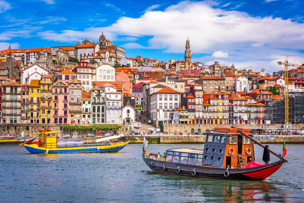 Porto’s iconic rabelo boats in the Douro River, flanked by the Old Town skyline.
