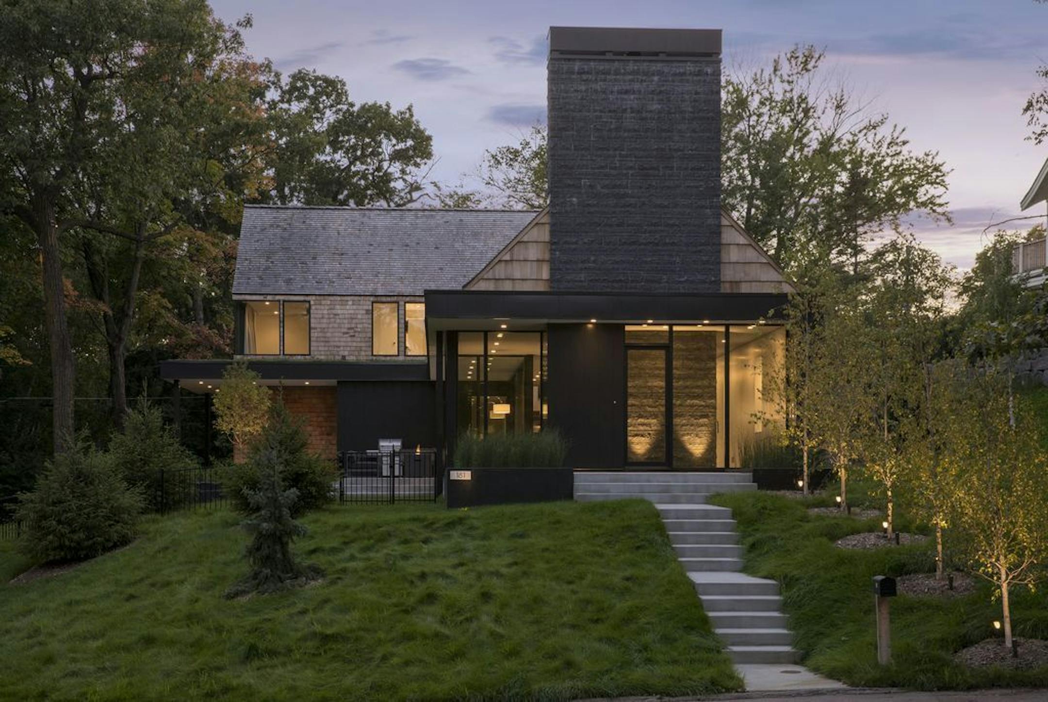 The charcoal-hued chimney and stone wall make a dramatic statement in the front entry of a new Wayzata home was designed by Peterssen/Keller Architecture..