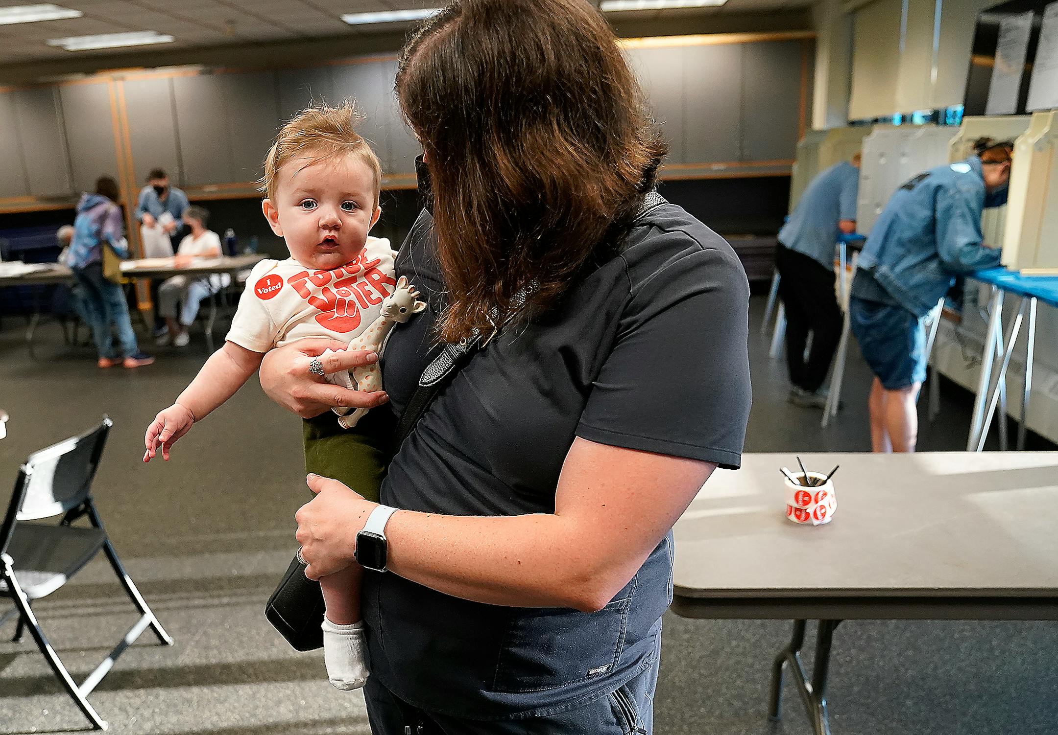 Voter Lydia Beattie of Minneapolis holds her son Faris, 6 months, after Beattie voted at Powderhorn Park during the primary election that includes the 5th congressional district Tuesday, Aug. 9, 2022 in Minneapolis.  "I think he enjoyed it,' Beattie said about Faris' first voting experience.