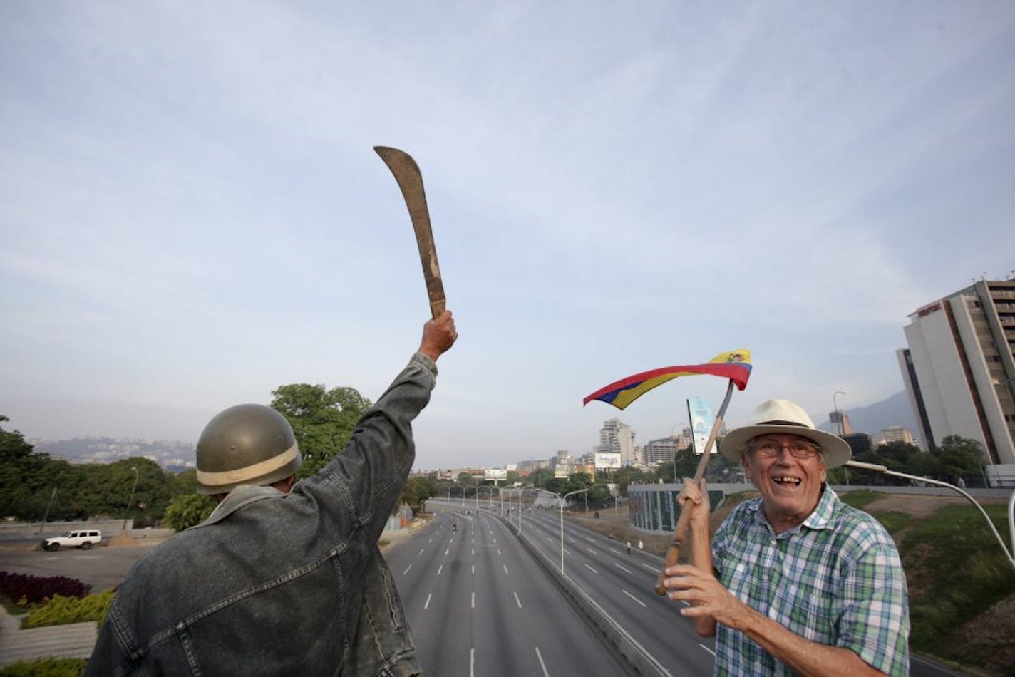 An opponent of Venezuela's President Nicolas Maduro raises a machete during an attempted military uprising outside the La Carlota airbase in Caracas, Venezuela, Tuesday, April 30, 2019. Venezuelan opposition leader Juan Guaidó and jailed opposition leader Leopoldo Lopez took to the streets with a small contingent of armed troops early Tuesday in a call for the military to rise up and oust Maduro.