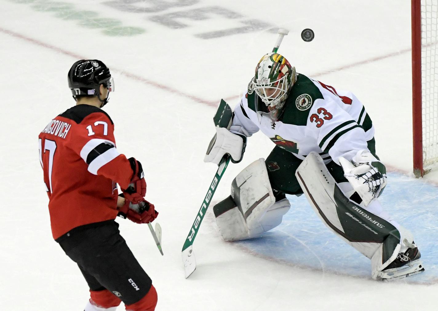 Minnesota Wild goaltender Cam Talbot, right, deflects a shot by New Jersey Devils center Yegor Sharangovich (17) in a shootout during an NHL hockey game Wednesday, Nov. 24, 2021, in Newark, N.J. The Wild defeated the Devils 3-2 in a shootout. (AP Photo/Bill Kostroun)