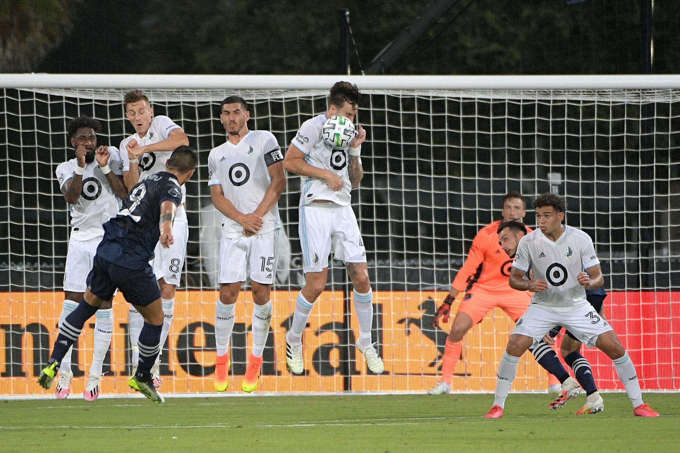 Minnesota United defender Jose Aja, center, gets hit in the face by the ball on a penalty kick by Sporting KC forward Alan Pulido (9) during Sunday's match.