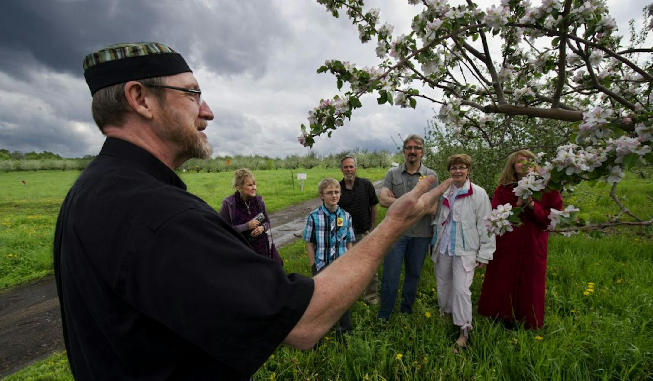 Pastor Steve Thompson of Hope Lutheran Church in Jordan offered a prayer at the "Blessing of the Blossoms" celebration at the reopened Minnesota Harvest orchard. In back are Donna Knox, ­Noah Knox, Kevin Breeggemann, Kevin Knox, Susan Kelly and Susan Mecredy.