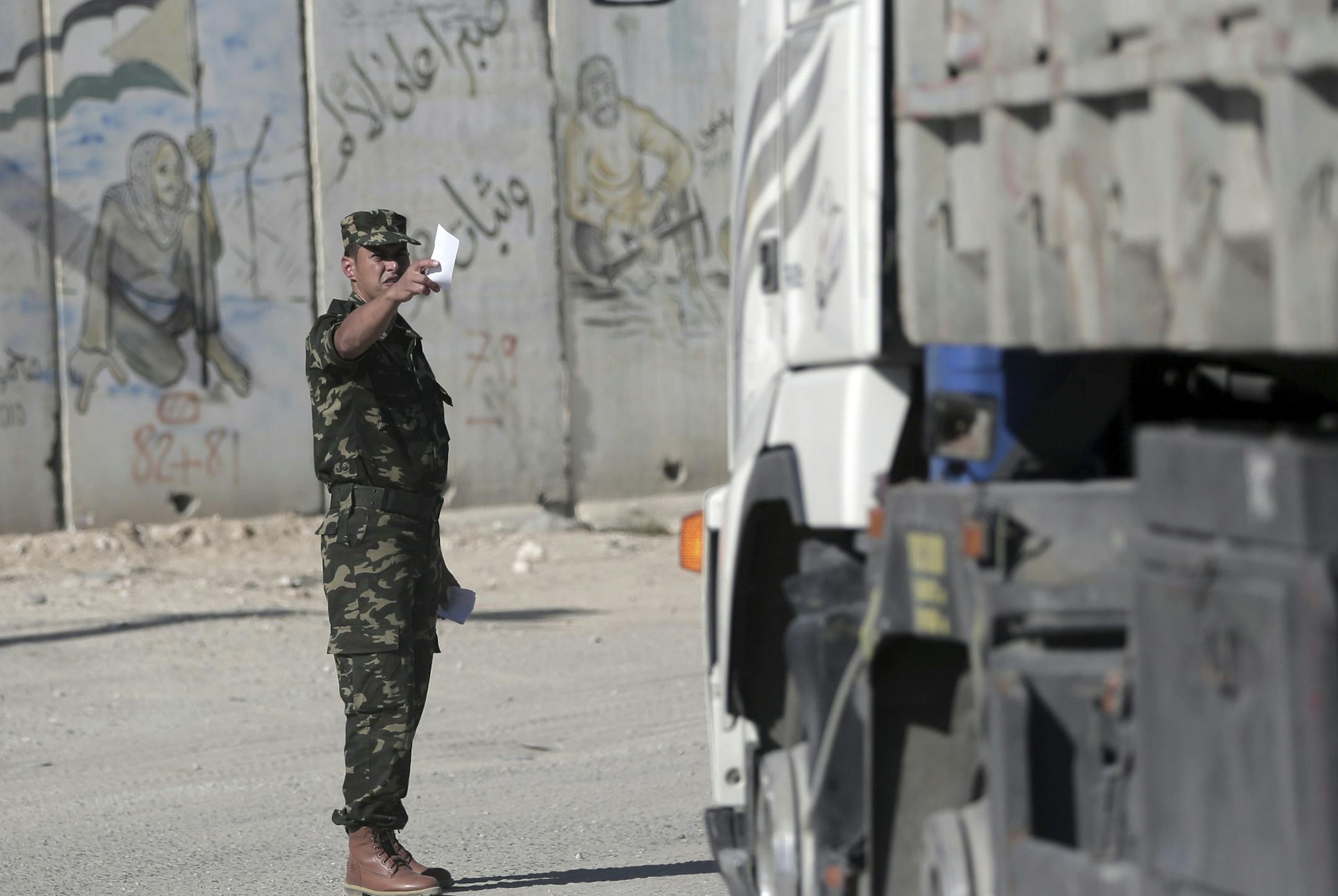 A Palestinian security officer controls traffic of imported goods at the Kerem Shalom border crossing on the Gaza Strip-Israel border, Wednesday, Nov. 1, 2017. The Islamic militant Hamas group has handed over control of Gaza's border crossings with Israel and Egypt to the internationally recognized Palestinian Authority. The handover was the first tangible step in implementing a reconciliation deal, with Egyptian mediation, between Hamas and the rival Fatah party, which controls the Palestinian