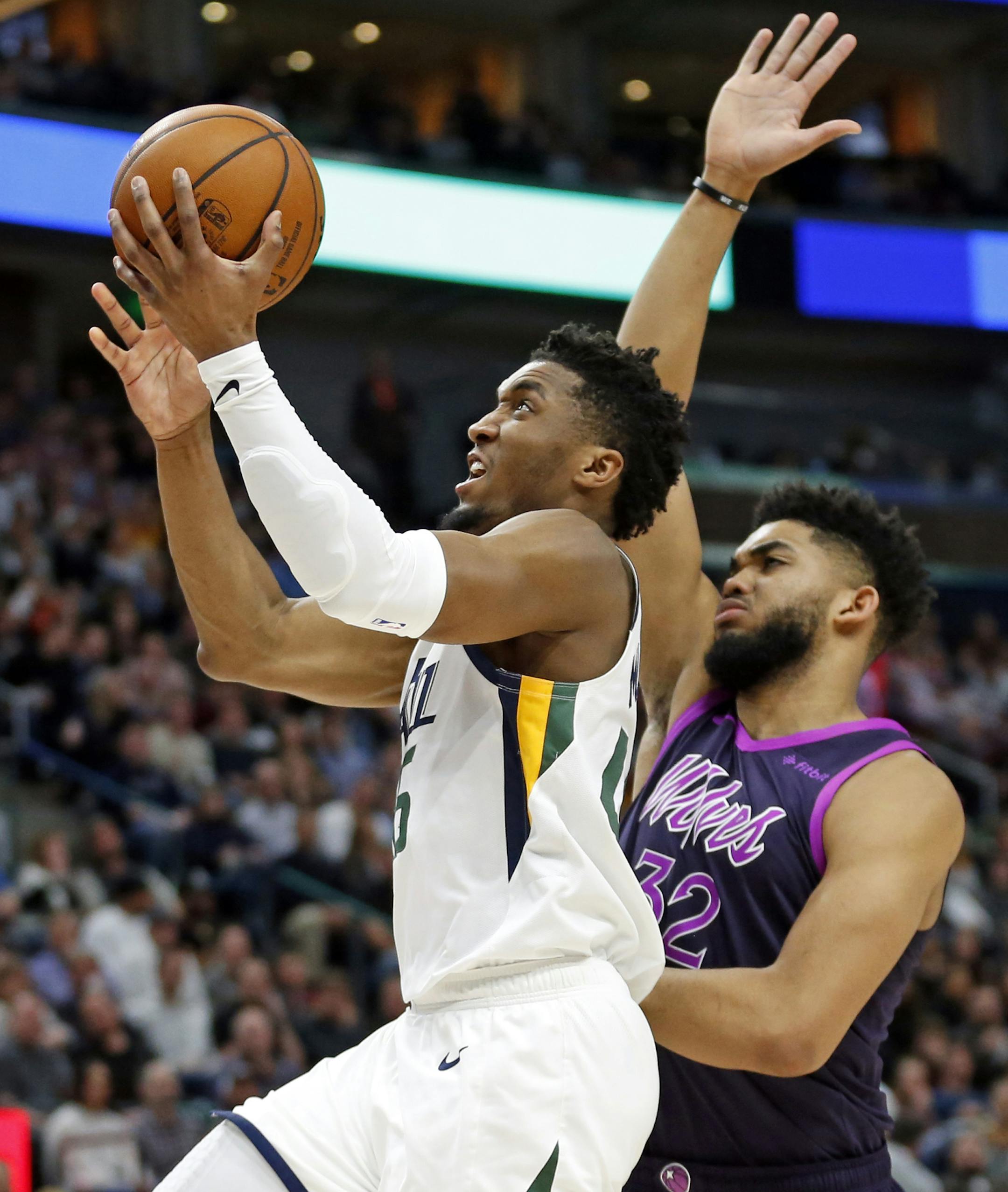 Utah Jazz guard Donovan Mitchell, left, goes to the basket as Minnesota Timberwolves center Karl-Anthony Towns, rear, defends in the second half during an NBA basketball game Thursday, March 14, 2019, in Salt Lake City. (AP Photo/Rick Bowmer)