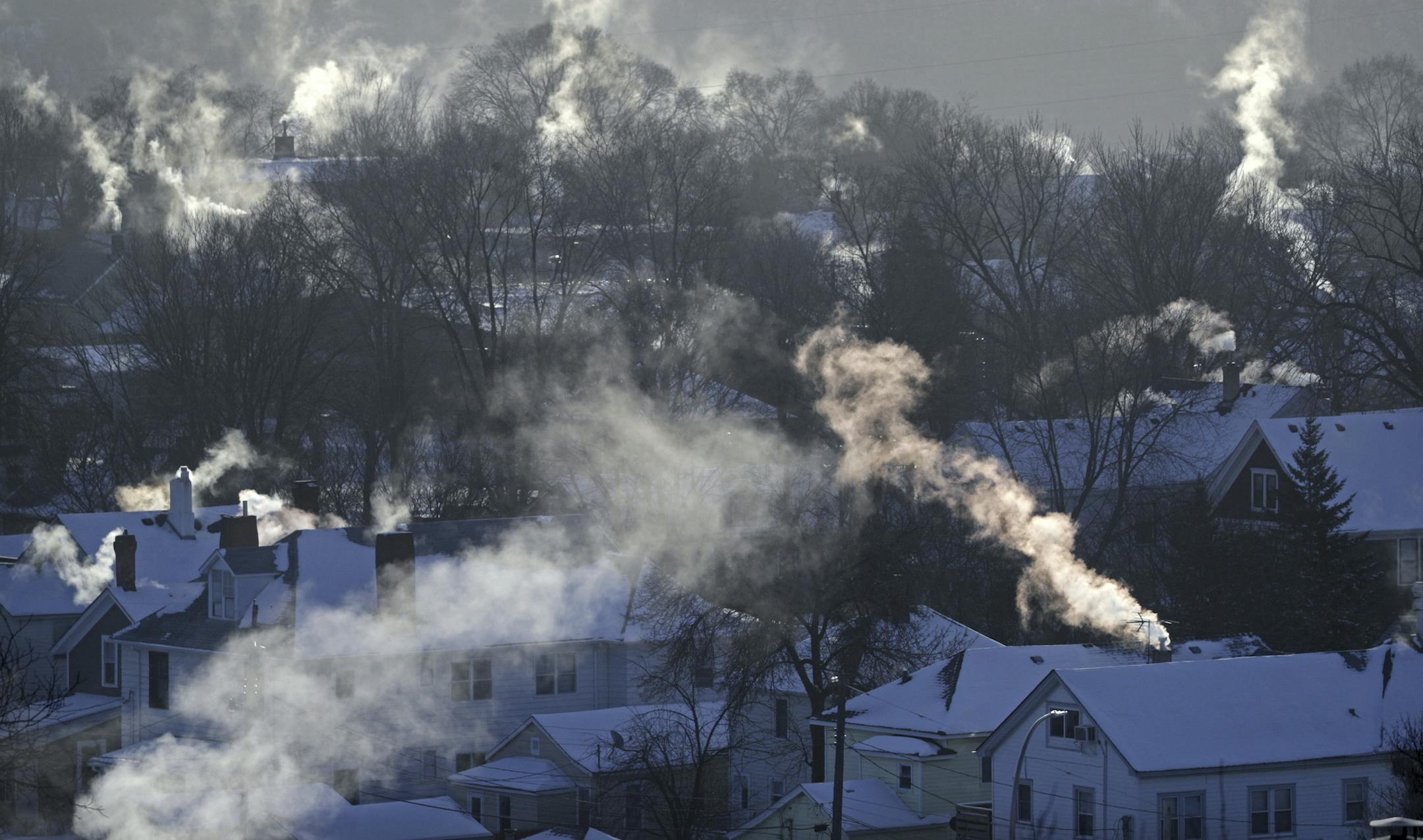 Smoke rises from the chimneys of homes in St. Paul's West 7th neighborhood Wednesday, Jan. 30, 2019, as furnaces tried to keep up with the record breaking cold, Wednesday, Jan. 30, 2019, in Minn. Xcel Energy says the extreme cold has caused some customers to lose natural gas service in central Minnesota and has the utility issuing an appeal to other customers to turn down their thermostats. (Brian Peterson/Star Tribune via AP)