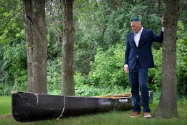 Erik Grams stands with his damaged canoe June 13 at his home in Ham Lake. Grams was part of a fishing group that went over Curtain Falls in the Bounda