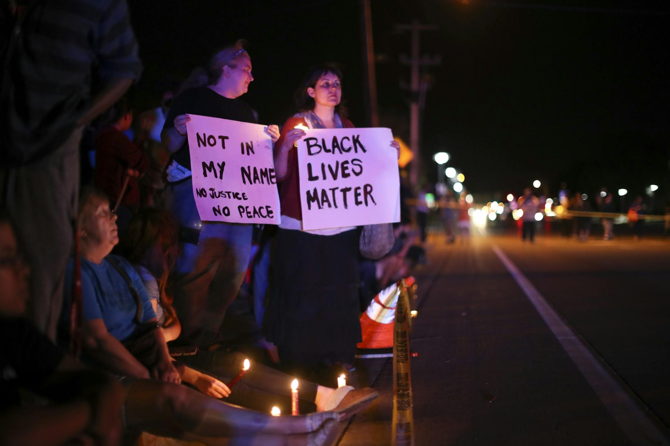 Demonstrators held signs across the street from the scene of a shooting Wednesday night in Falcon Heights.