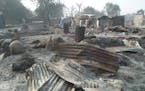 People walk past burnt out houses following an attack by Boko haram in Dalori village 5 kilometers (3 miles) from Maiduguri, Nigeria , Sunday Jan. 31,