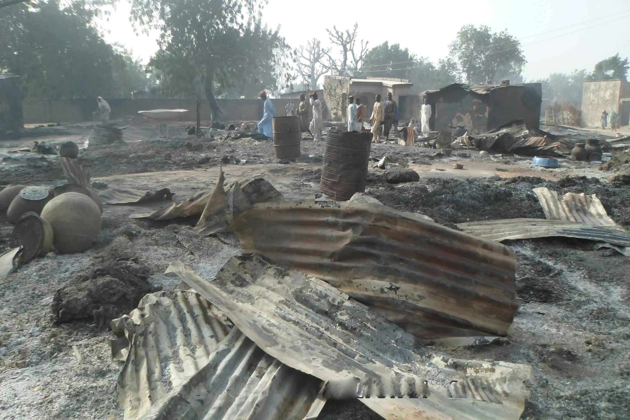 People walk past burnt out houses following an attack by Boko haram in Dalori village 5 kilometers (3 miles) from Maiduguri, Nigeria , Sunday Jan. 31, 2016. A survivor hidden in a tree says he watched Boko Haram extremists firebomb huts and listened to the screams of children among people burned to death in the latest attack by Nigeria’ s homegrown Islamic extremists. (AP Photo/Jossy Ola)