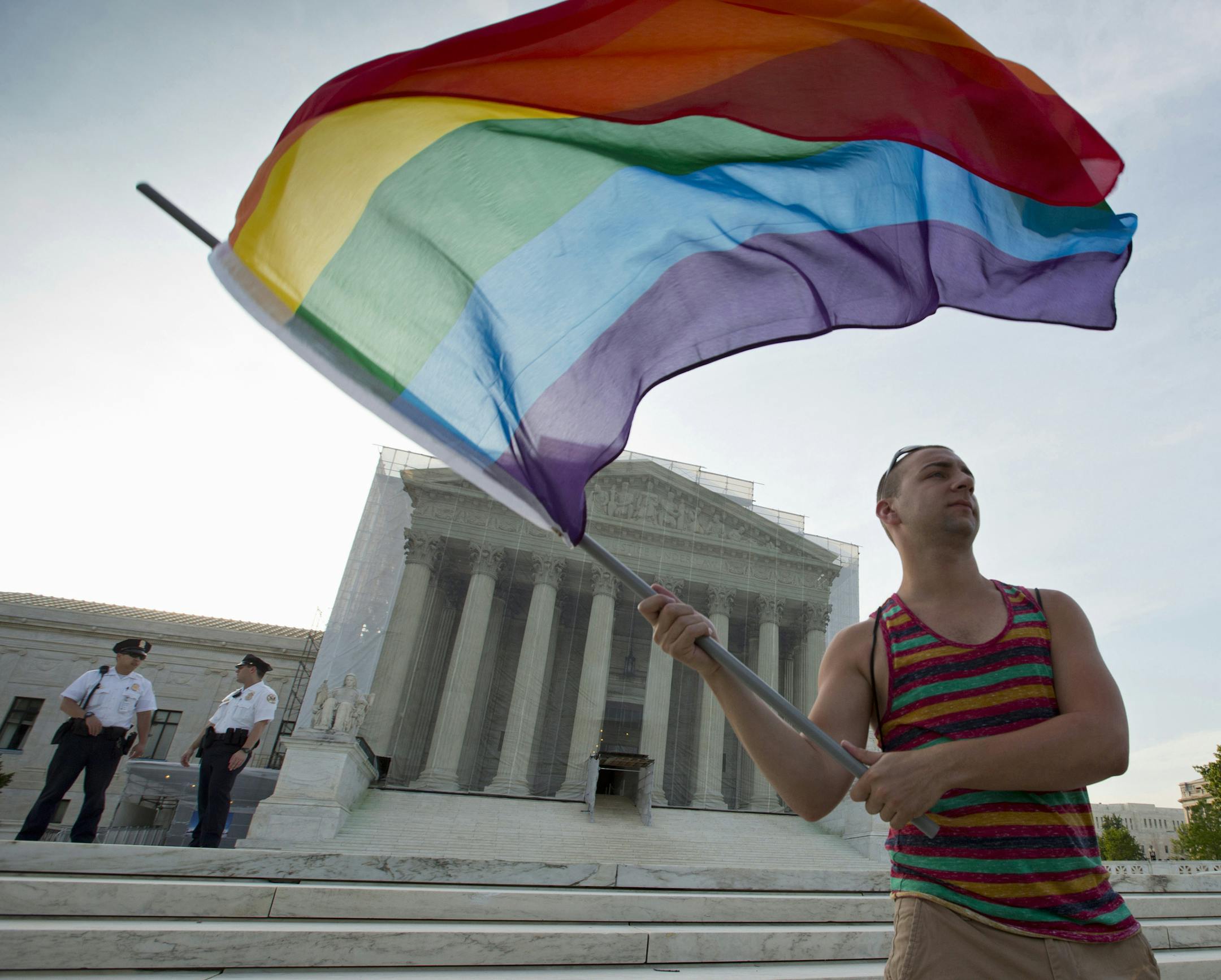 FILE - In this June 26, 2013, file photo, gay rights advocate Vin Testa waves a rainbow flag in front of the Supreme Court in Washington. It was announced Friday that the Supreme Court will decide gay marriage issue this term. (AP Photo/J. Scott Applewhite, File)