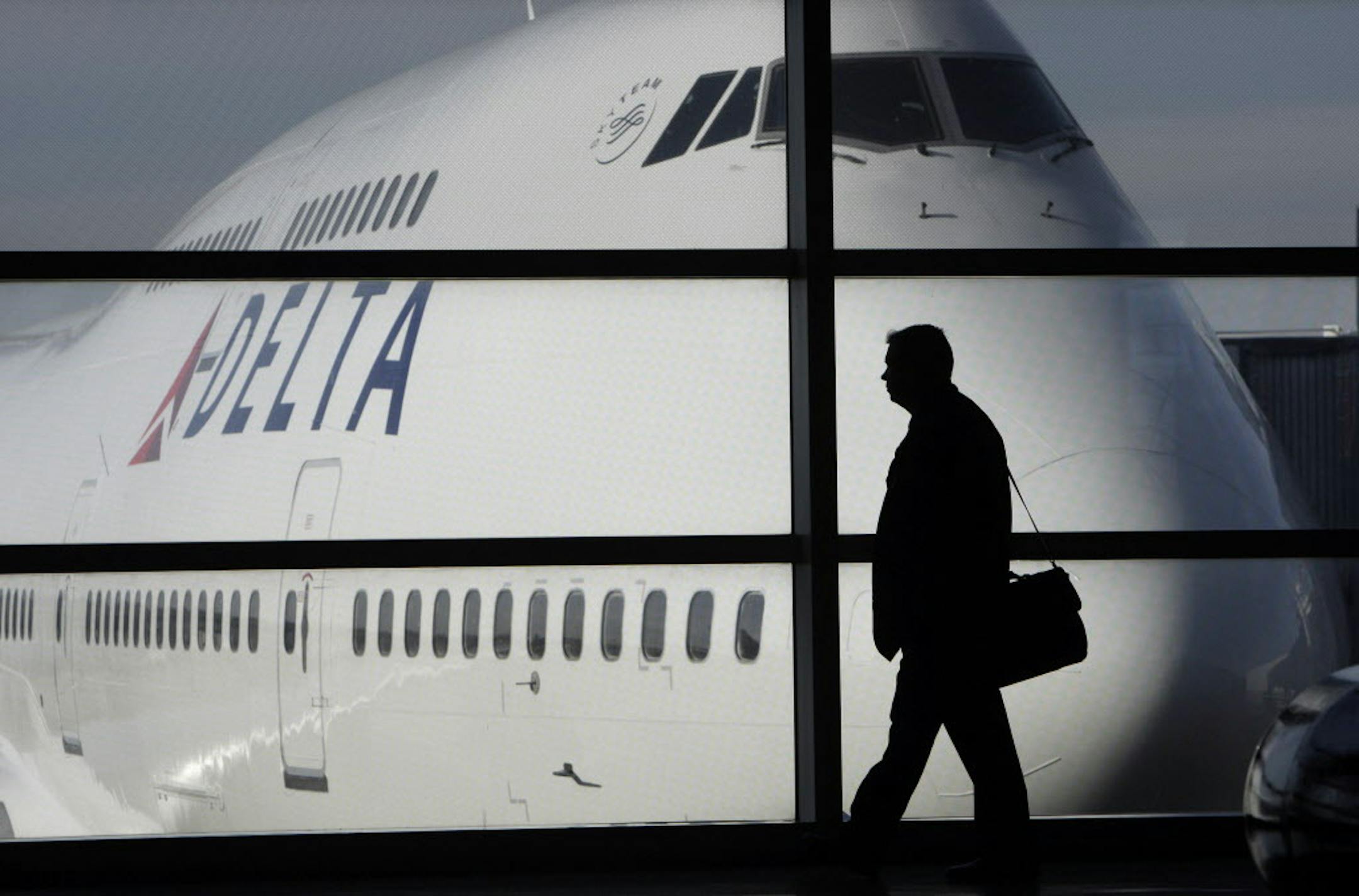 FILE - In this Jan. 21, 2010 file photo, a passenger walks past a Delta Airlines 747 aircraft in McNamara Terminal at Detroit Metropolitan Wayne County Airport in Romulus, Mich. Fares are higher, demand is up and the airlines have established a steady revenue stream from add-on fees for baggage, pillows and food. (AP Photo/Paul Sancya, file) ORG XMIT: MIN2012090615575792