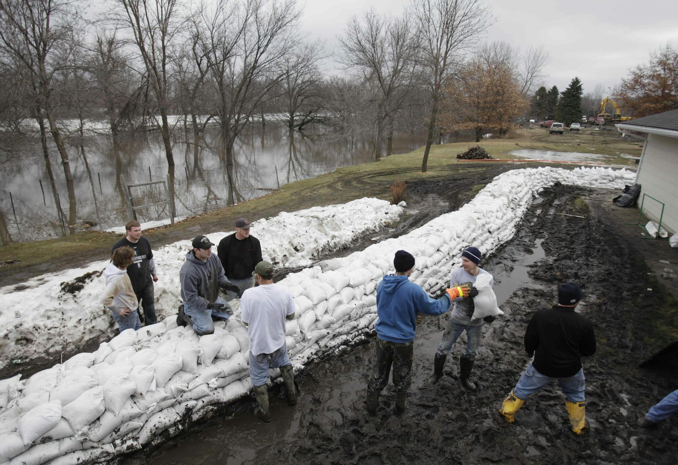 In this March 24, 2009 file photo, neighborhood workers pile sandbags around the Schell home in the hope of holding back floodwaters of the Red River seen close behind them in Fargo, N.D. Opponents of a nearly $2 billion Red River flood control project that would mainly benefit North Dakotaís largest city, Fargo, have enlisted the support of two powerful allies, including Minnesota Gov. Mark Dayton.