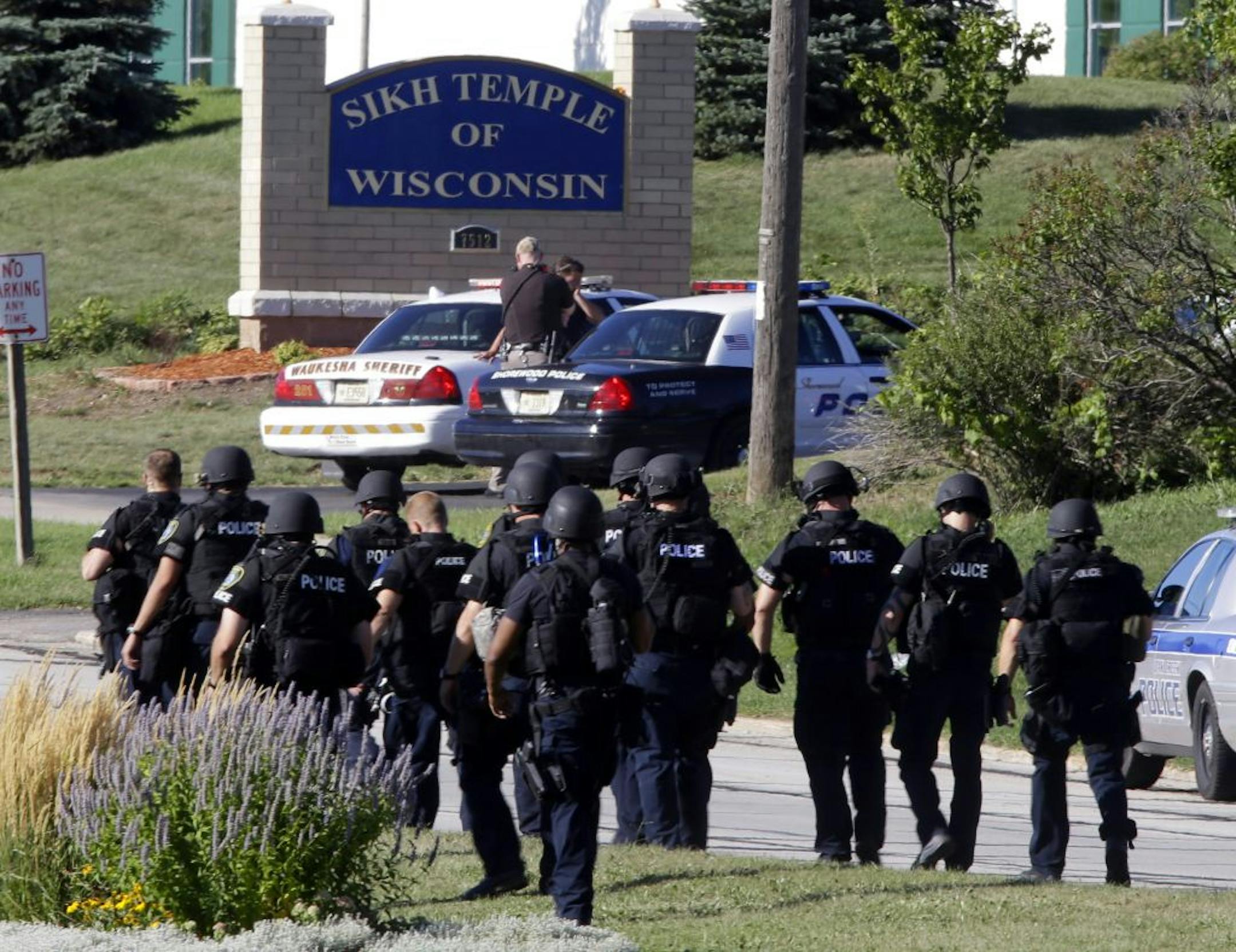 Police walk near the Sikh Temple of Wisconsin in Oak Creek, Wis., after a shooting Sunday, Aug 5, 2012. A gunman killed six people at the suburban Milwaukee temple.