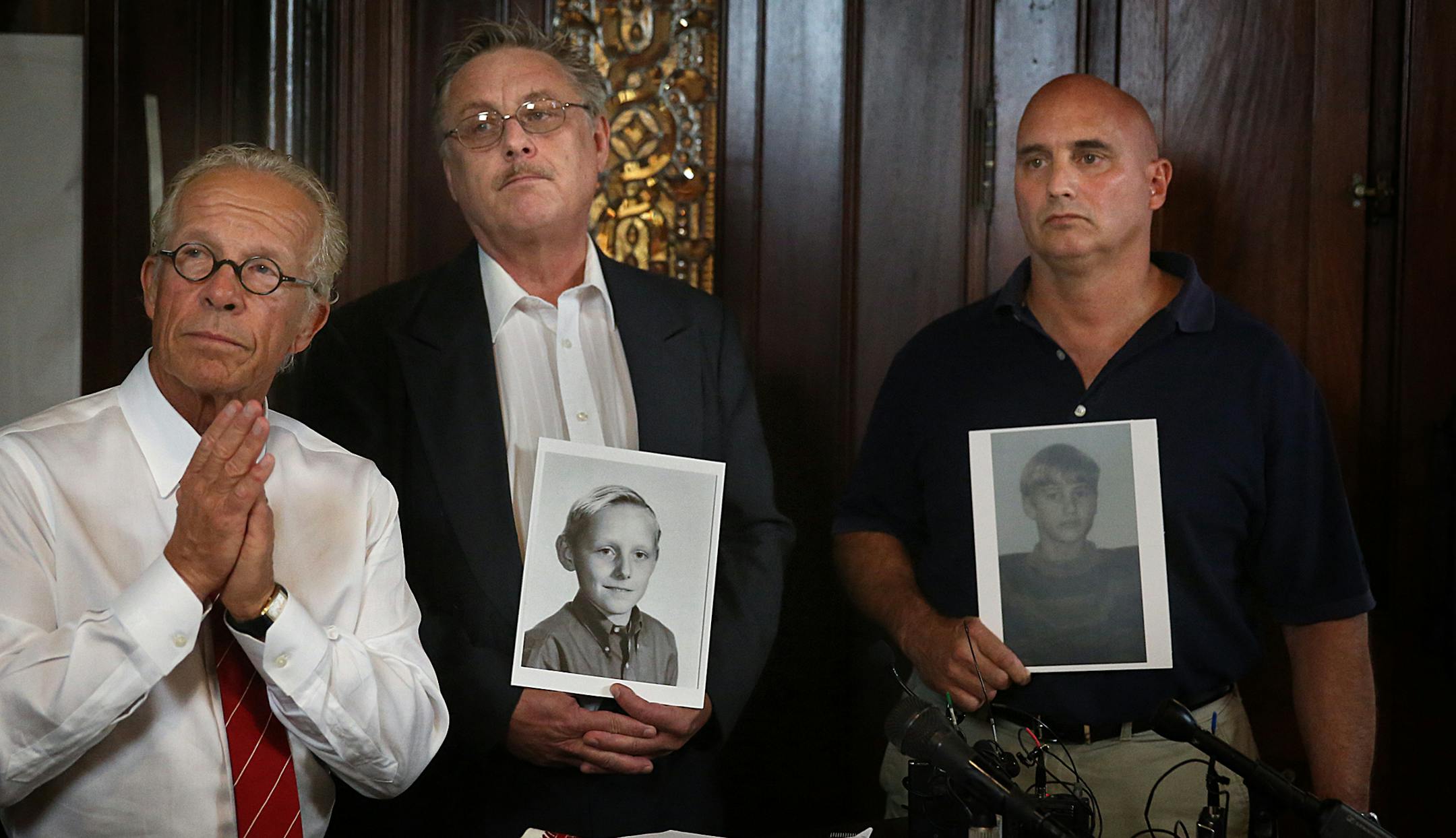 Former Boy Scouts Steven Josephson (middle) and David Lundquist (right), who allege they were abused by scout leaders, held photographs of themselves as children during a news conference with attorney Jeff Anderson (left). Anderson announced two new sex abuse lawsuits against Boy Scouts of America, the first ever public nuisance claims against the organization.