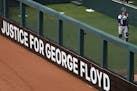 A sign calling for justice for George Floyd sat in the outfield outside the bullpen during the Twins home opener against the Seattle Mariners
