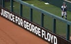 A sign calling for justice for George Floyd sat in the outfield outside the bullpen during the Twins home opener against the Seattle Mariners