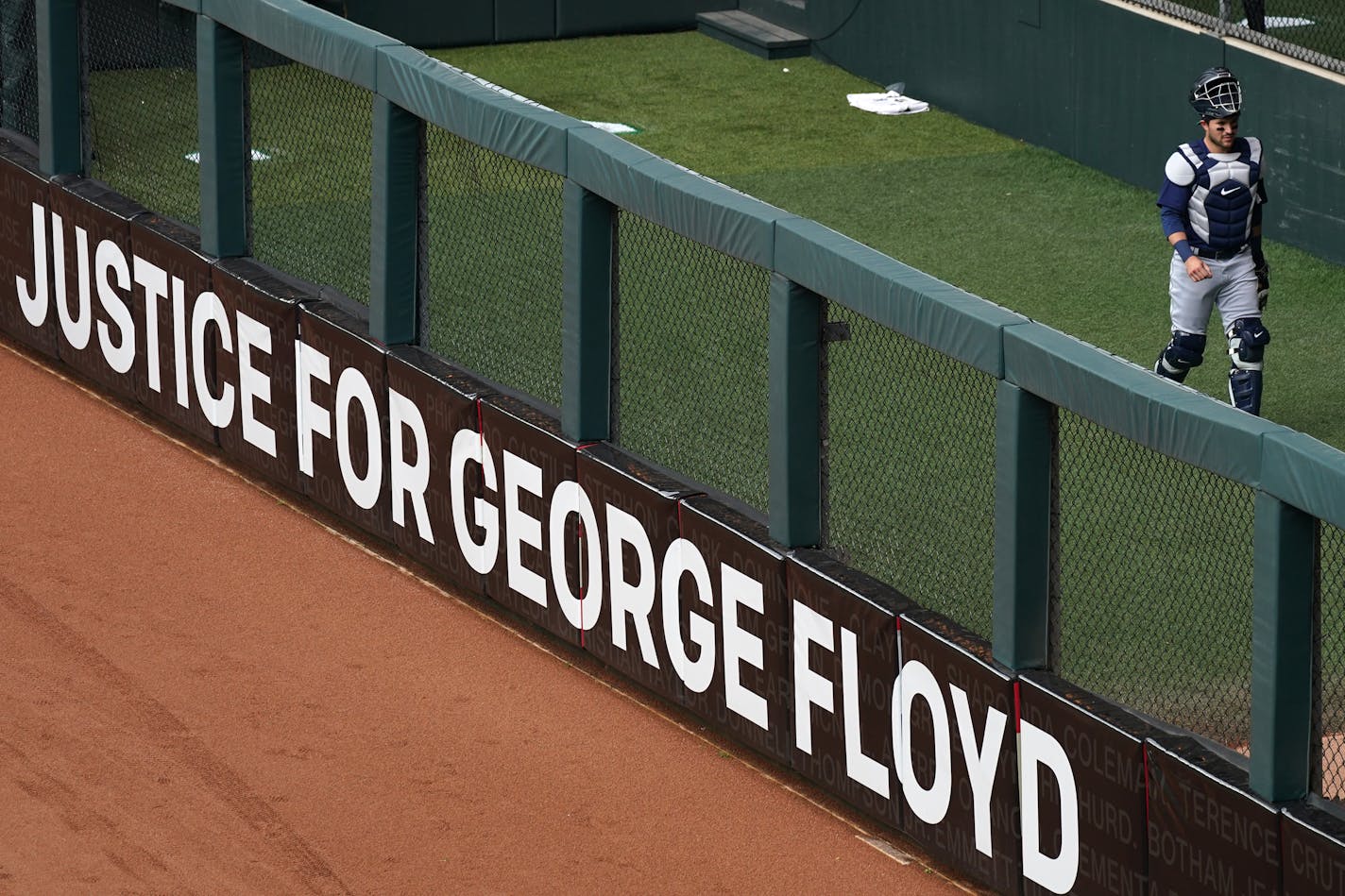 A sign calling for justice for George Floyd sat in the outfield outside the bullpen during the Twins home opener against the Seattle Mariners