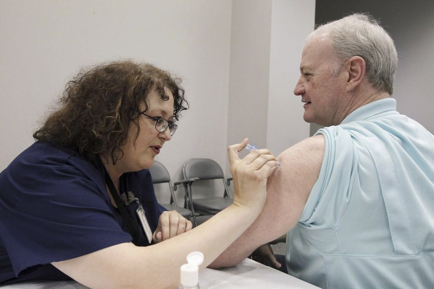 FILE - In this file photo taken Oct. 17, 2012, Bill Staples, a Mississippi Department of Health employee, is given an intradermal shot of flu vaccine by registered nurse Rosemary Jones, also with the health department, in Jackson, Miss. A survey by Centers for Disease Control and Prevention researchers found that in 2011, more than 400 U.S. hospitals required flu vaccinations for their employees and 29 hospitals fired employees that were not vaccinated against the virus.