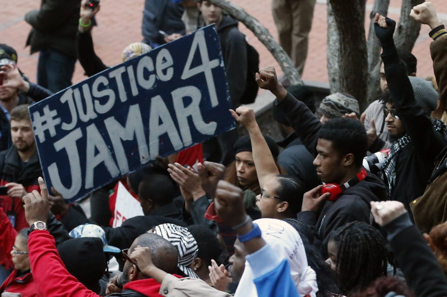 FILE - In this March 30, 2016 photo, demonstrators raise their fists in the air at the Government Center in Minneapolis during a protest over two Minneapolis police officers fatally shooting Jamar Clark, a black man, in November 2015. Two Minneapolis police officers followed proper procedure in a confrontation that led to the fatal shooting of Clark in November, and won't face discipline, the city's police chief announced Friday, Oct. 21. (AP Photo/Jim Mone, File)